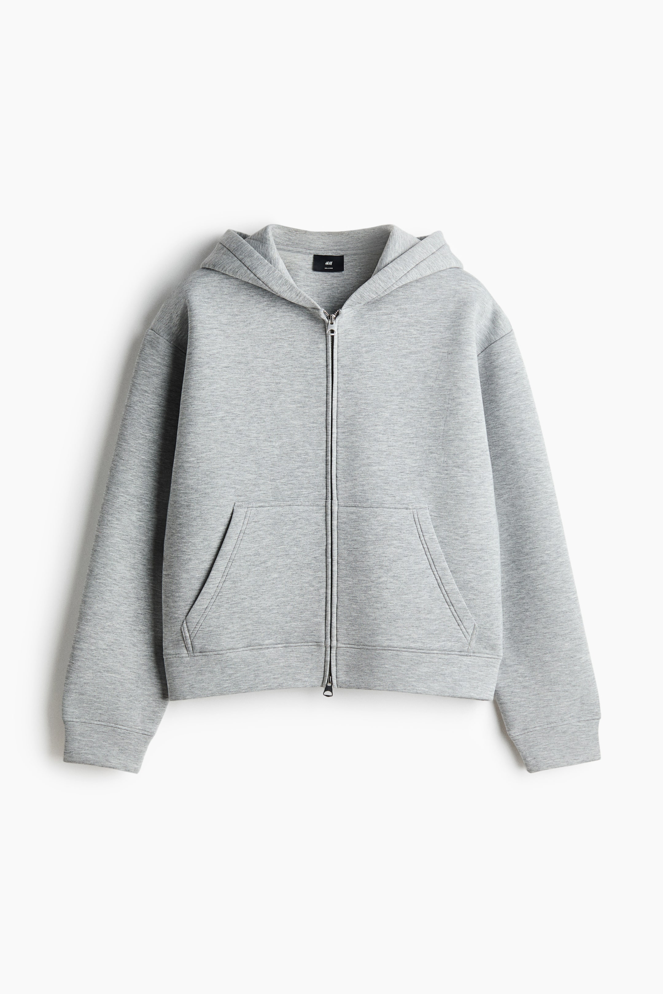 View larger image: A gray boxy-style zip-through hoodie in scuba fabric is shown from the front, featuring a loose fit with dropped shoulders, a hood, a full front zipper, and an open kangaroo pocket.