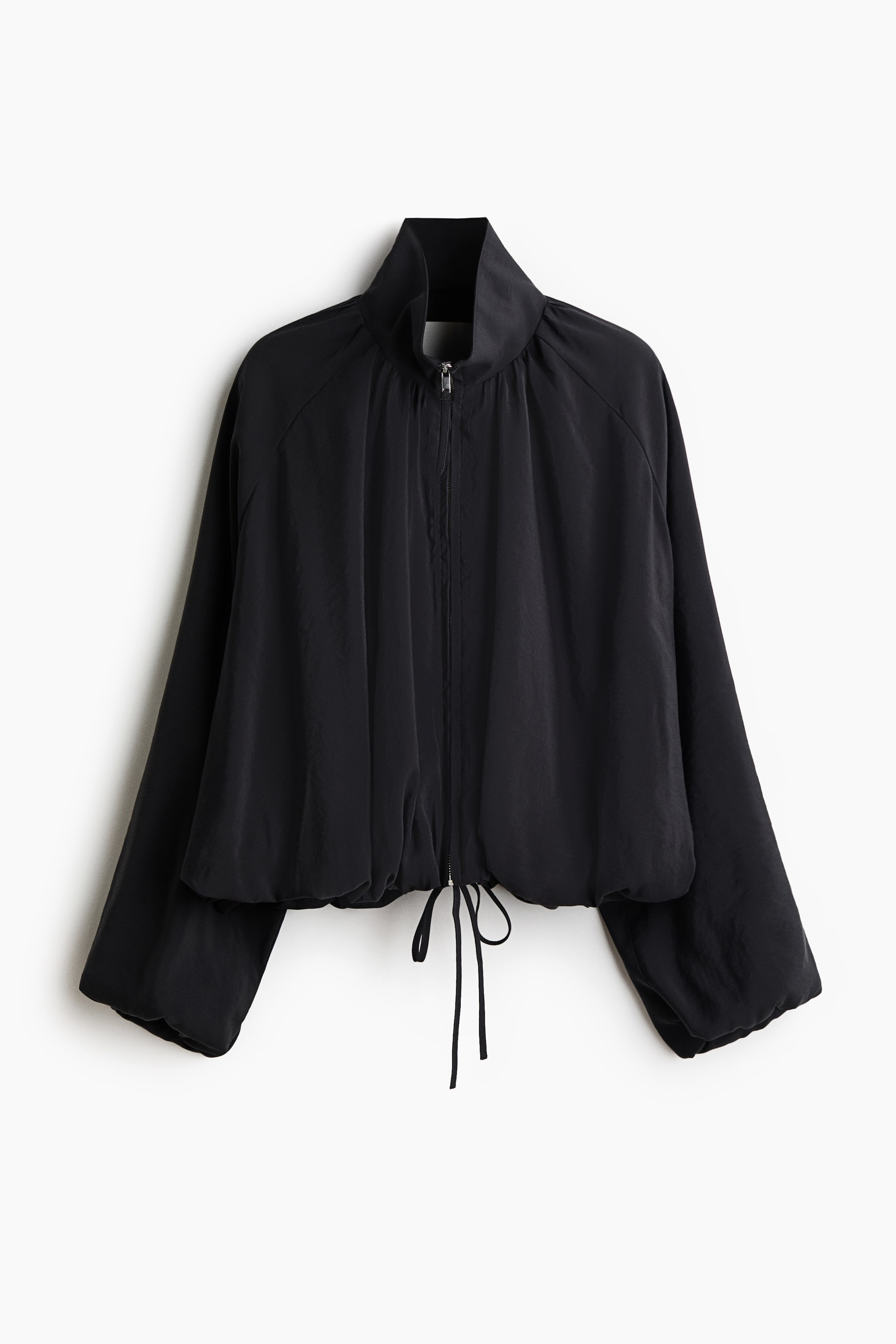 View larger image: A black cropped jacket showcases its front view, highlighting a high stand collar and a silver full-length zipper. It is crafted with loose raglan sleeves and a cinched drawstring hem, forming a gathered silhouette in a lightweight, slightly crinkled fabric.
