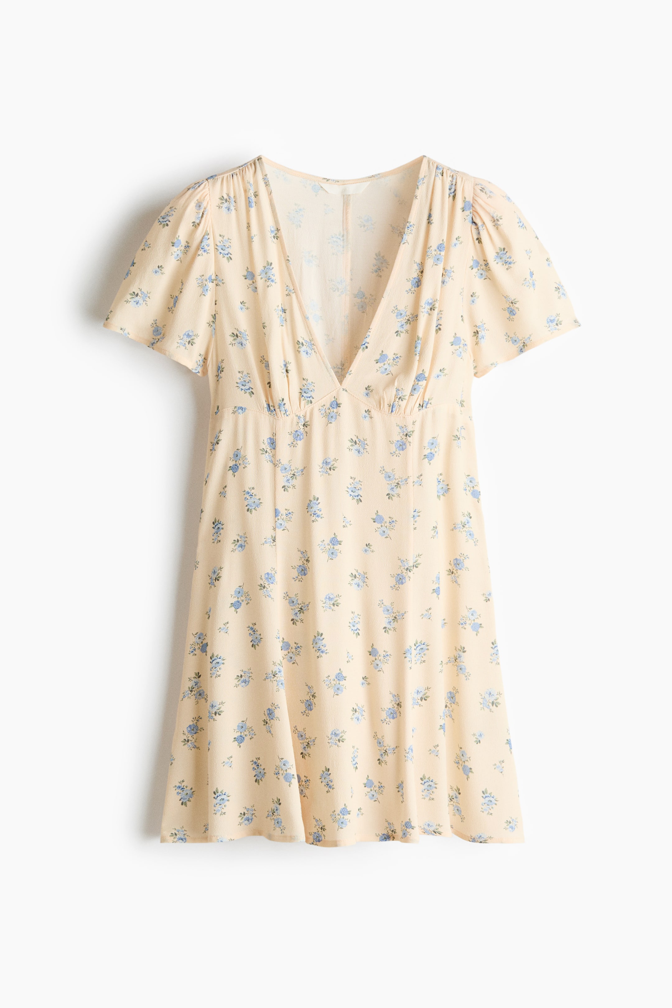 View larger image: The viscose dress with a flared skirt showcases a cream backdrop adorned with a blue floral pattern. It features a deep V-neckline and short gathered sleeves. The silhouette is accentuated by an elasticized waist, cascading into a flared skirt.