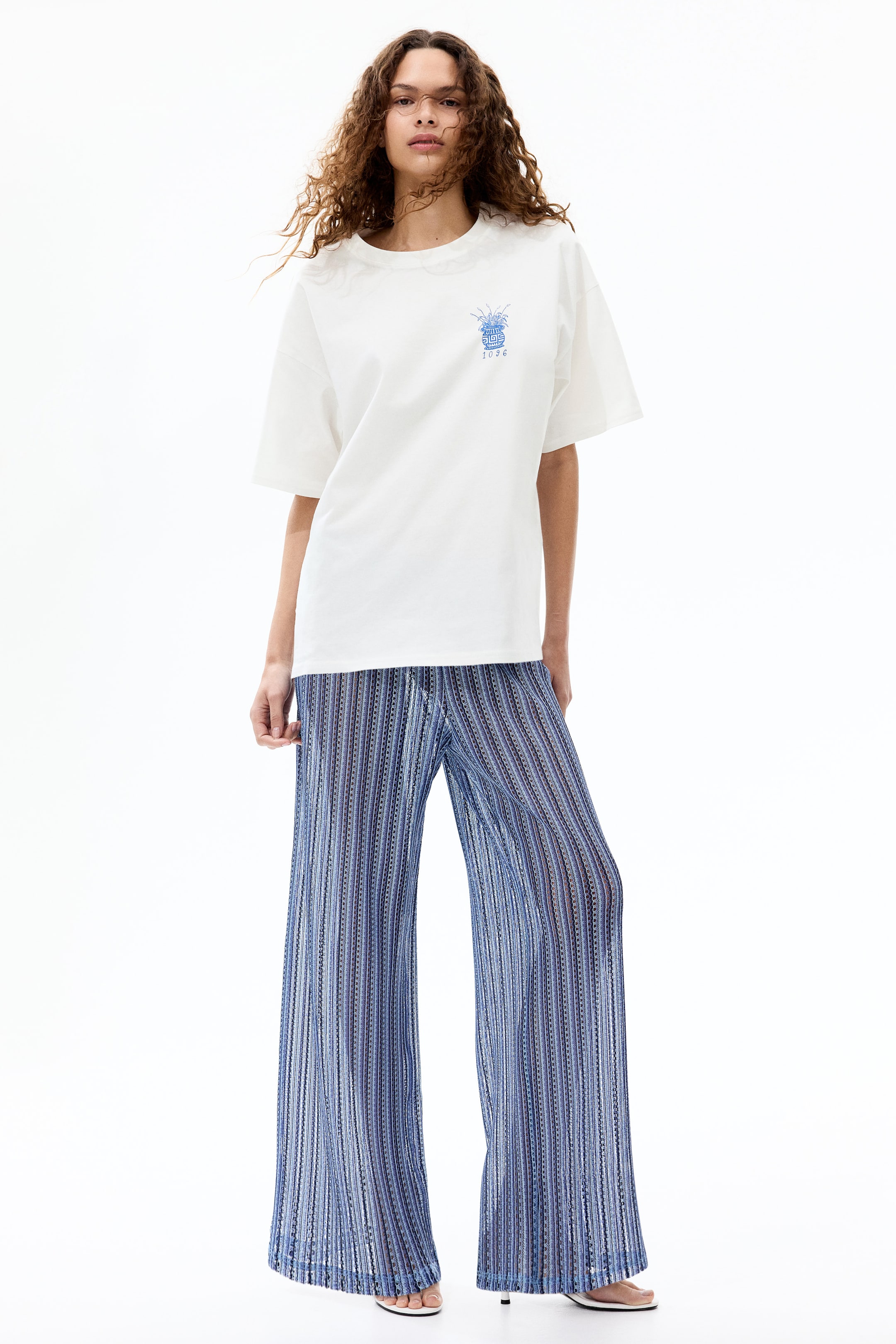 View larger image: A white oversized t-shirt with short sleeves and a crew neck features a blue graphic of a potted plant with the number 1026 on the left chest.