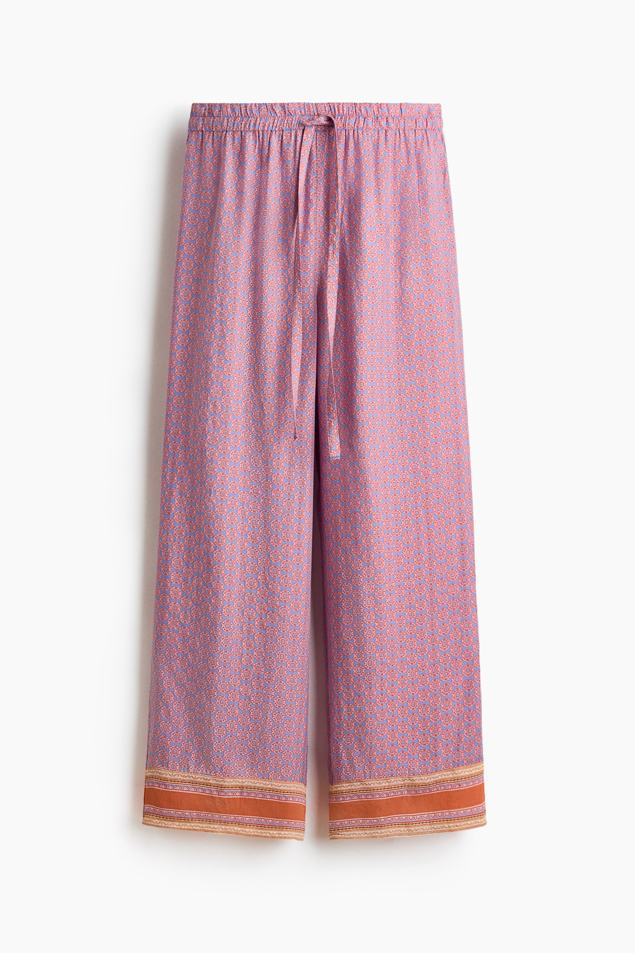 View larger image: The pants are positioned front-facing, showcasing a light purple and reddish-orange geometric design all over. They come with an elasticated waistband complemented by a central drawstring tie, while the bottom hem is highlighted by a wide, orange-brown patterned border.