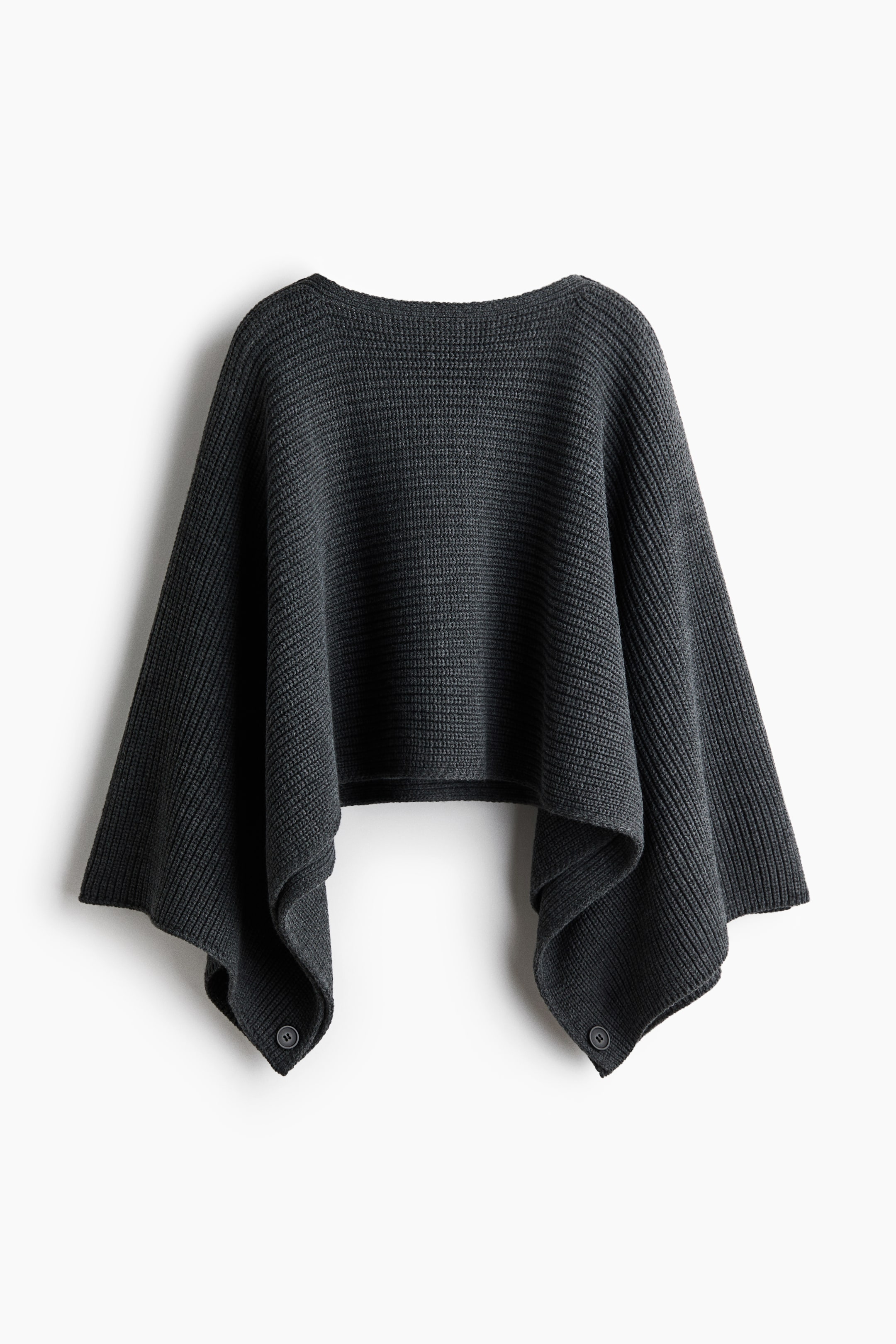 View larger image: A dark grey ribbed knit poncho is facing front, showcasing a wide boat neckline, a cropped centre hem, and long, draped sides. The side panels drape downward and feature a single button closure at each bottom corner.