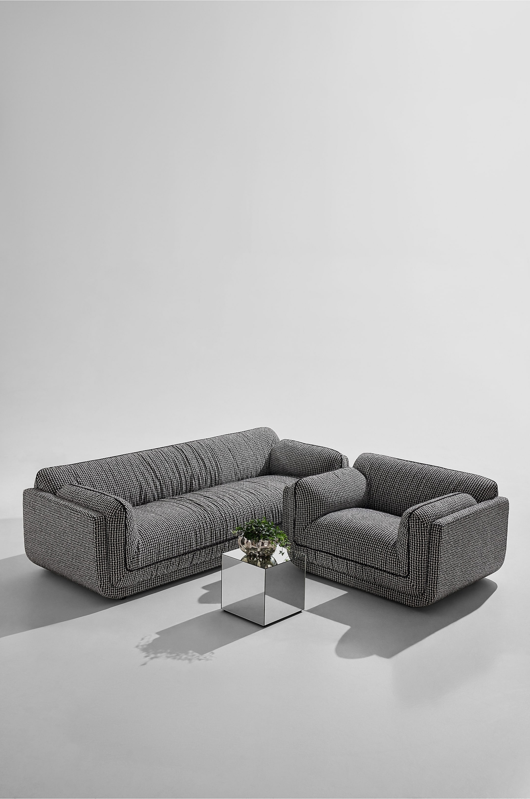 Visa större bild: En soffa och en fåtölj har matchande svart och vit mönstrad klädsel. Båda möblerna visar upp rundade, mjuka former med en låg profilbas och mörka passpoaler som markerar deras kanter, och är något vinklade mot betraktaren.