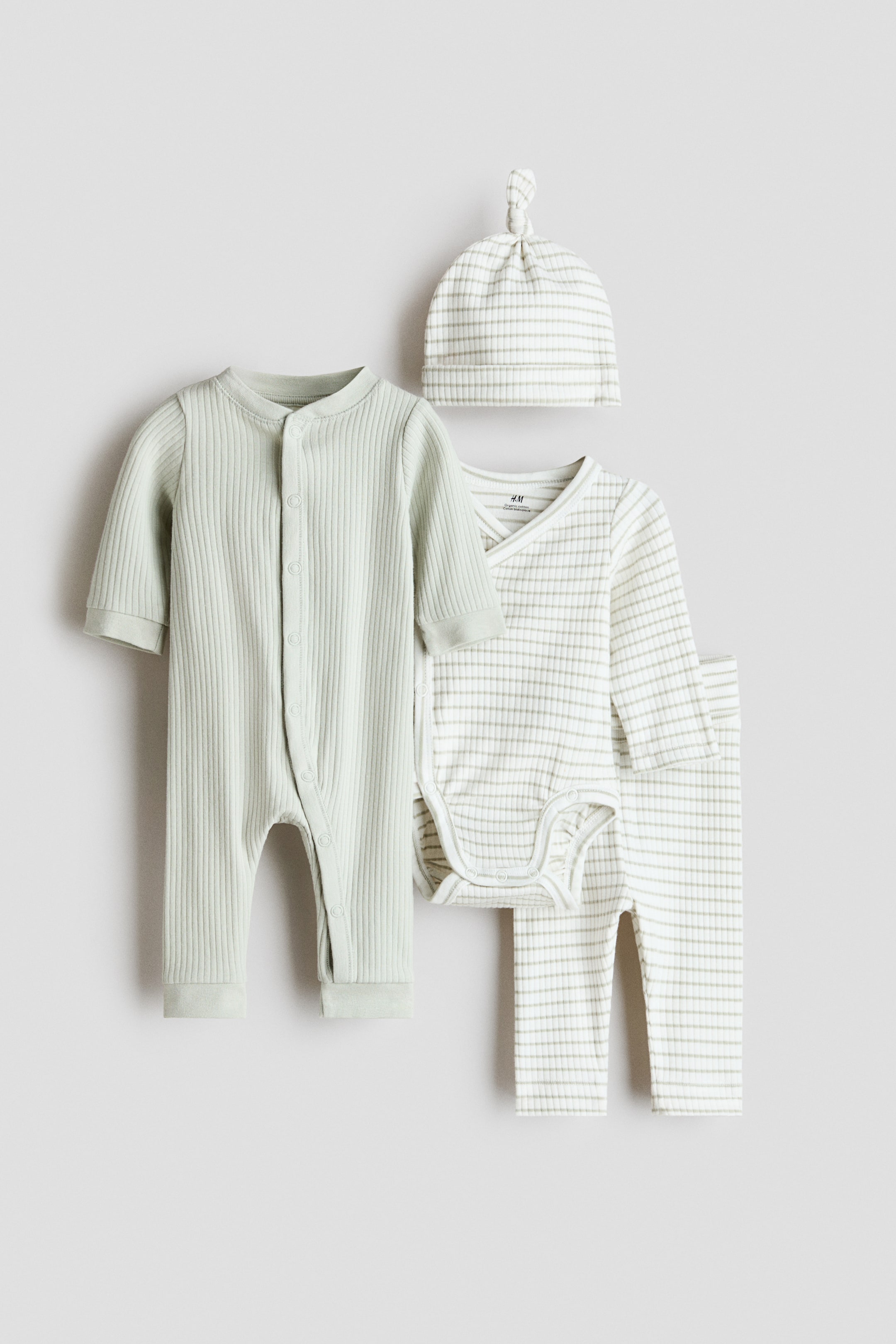 View larger image: A collection of baby clothes is showcased, featuring a light green ribbed long-sleeved romper with front and inner leg snap buttons, and a white and light green striped ribbed set comprising a long-sleeved wrap-style bodysuit with crotch snap buttons, matching pants, and a hat with a knotted top.