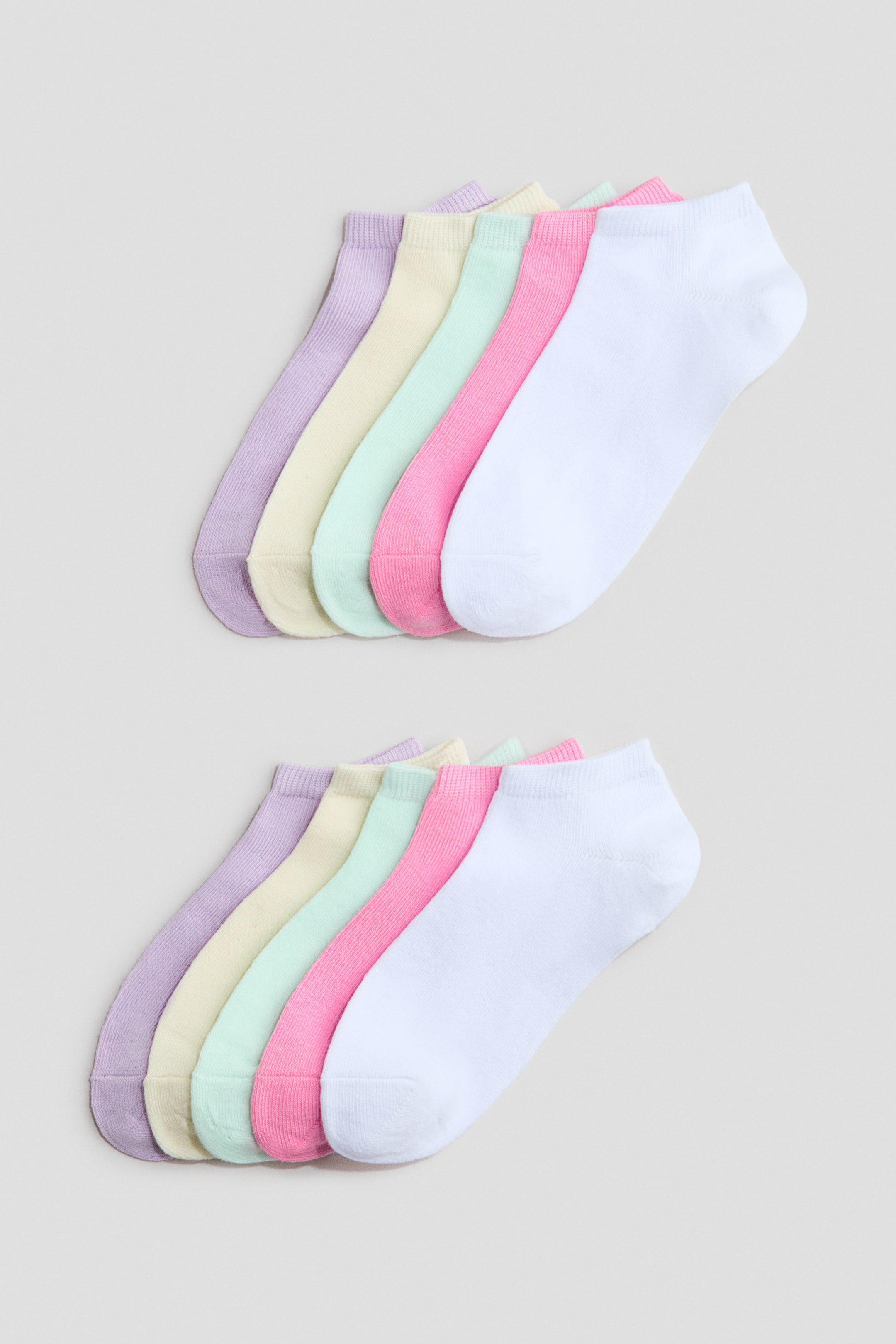 View larger image: Trainer socks are showcased in two fanned-out sets, each presenting five distinct pastel shades: lilac, pale yellow, mint green, pink, and white. These low-cut, fine-knit socks come with elasticated tops.