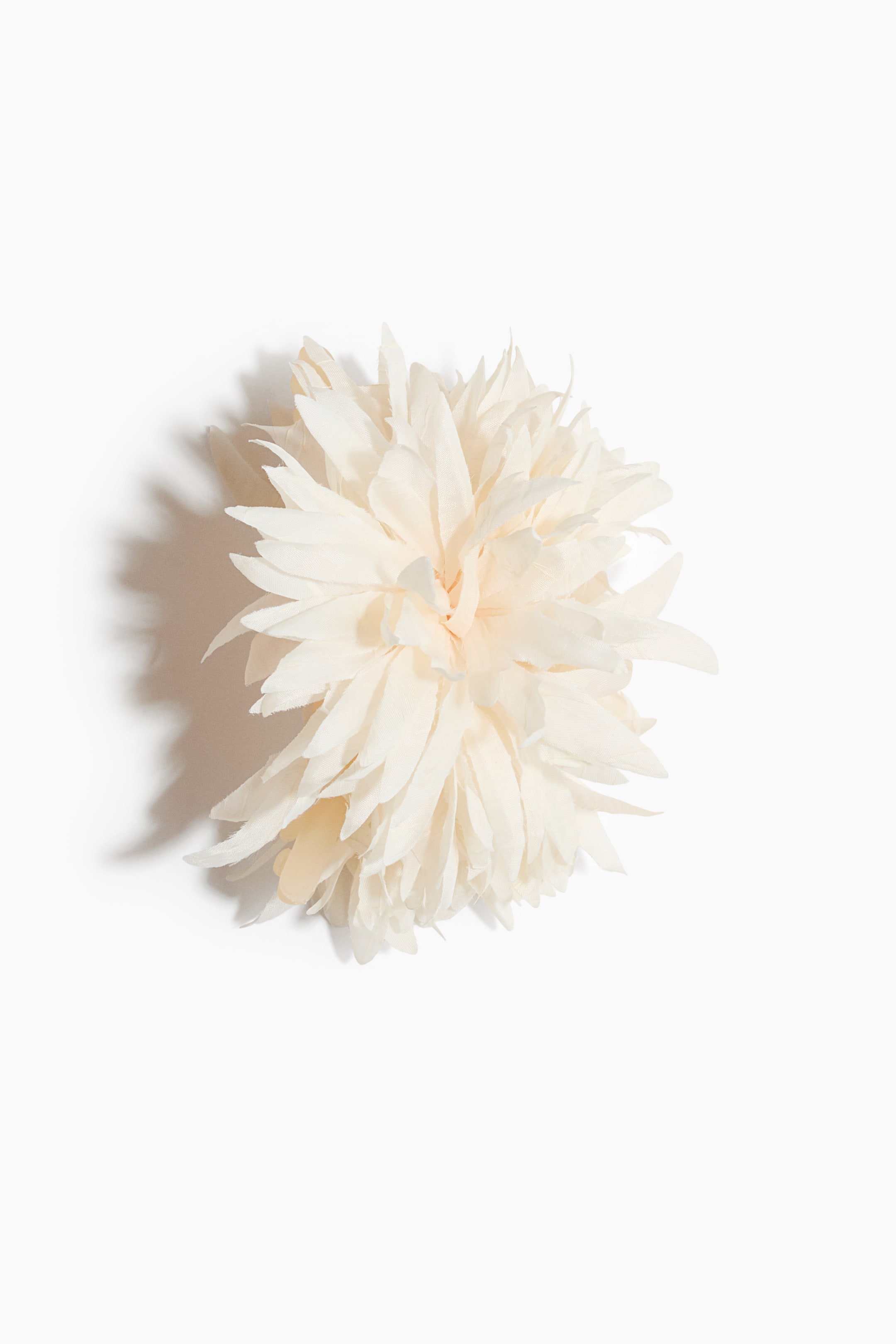 View larger image: A cream-coloured decorative item showcases its layered construction, featuring numerous individual, pointed pieces radiating outwards from a central core, creating a voluminous and textured appearance.