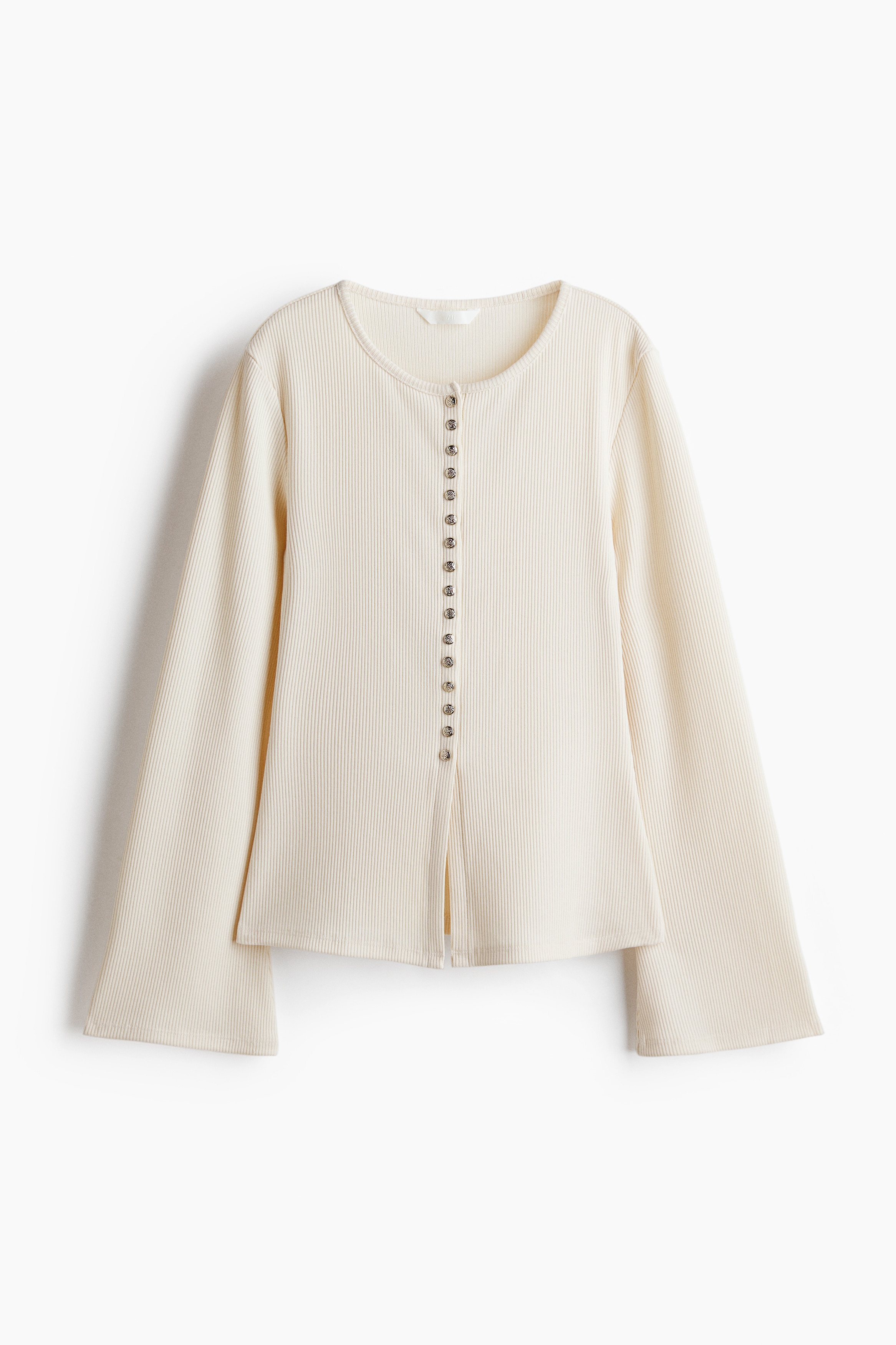 A fitted, off-white rib-knit cardigan is being worn by the model, featuring a round neckline and a row of metallic, hammered-finish press studs down the centre front. The close-up view highlights the fine ribbed texture and the detailed buttons of the garment.