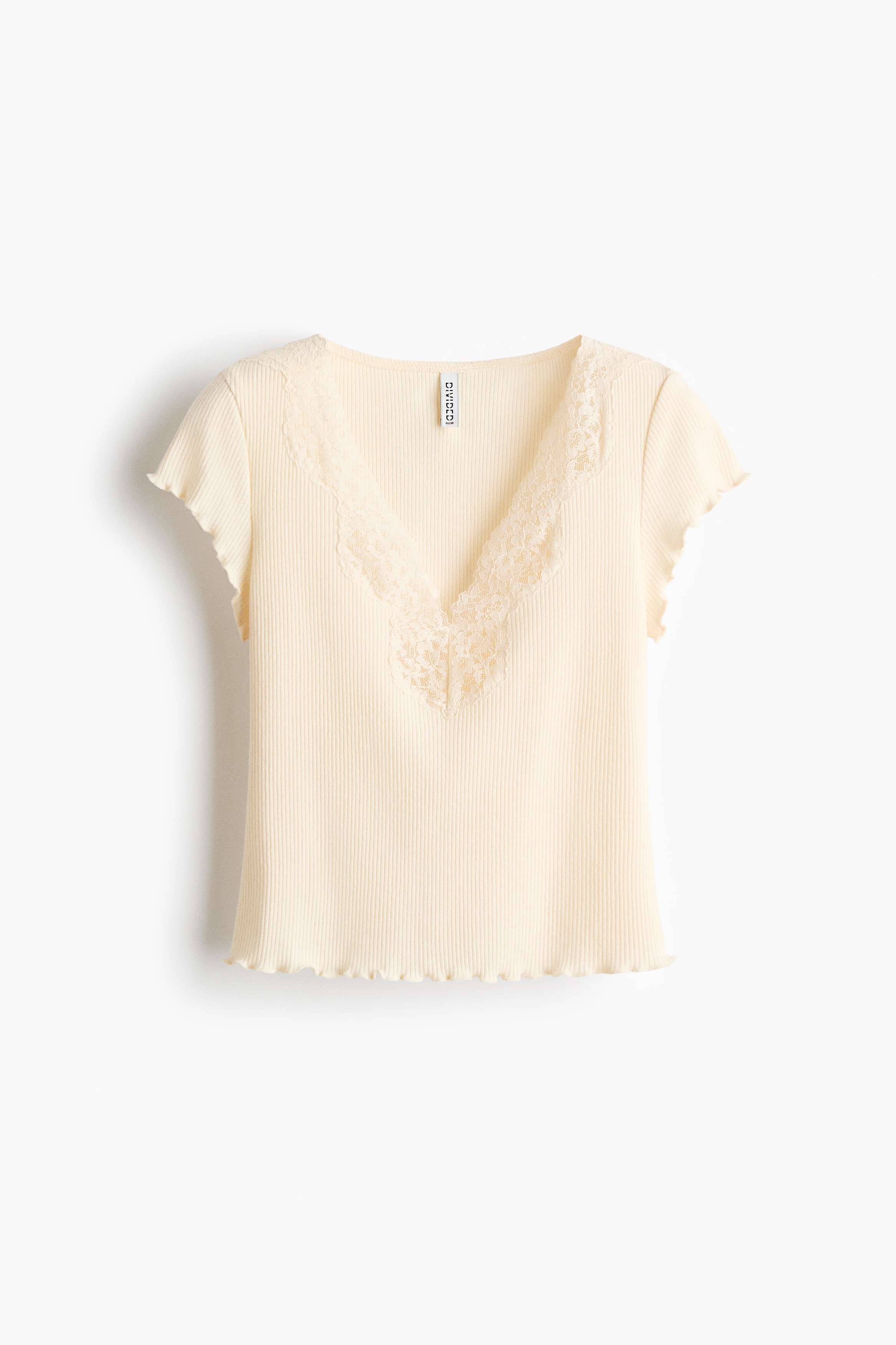 A fitted, cream-colored ribbed jersey top featuring a floral lace-trimmed V-neck, cap sleeves, and a wavy overlocked hem is being worn by the model. The top is styled with light-blue, wide-leg denim jeans.