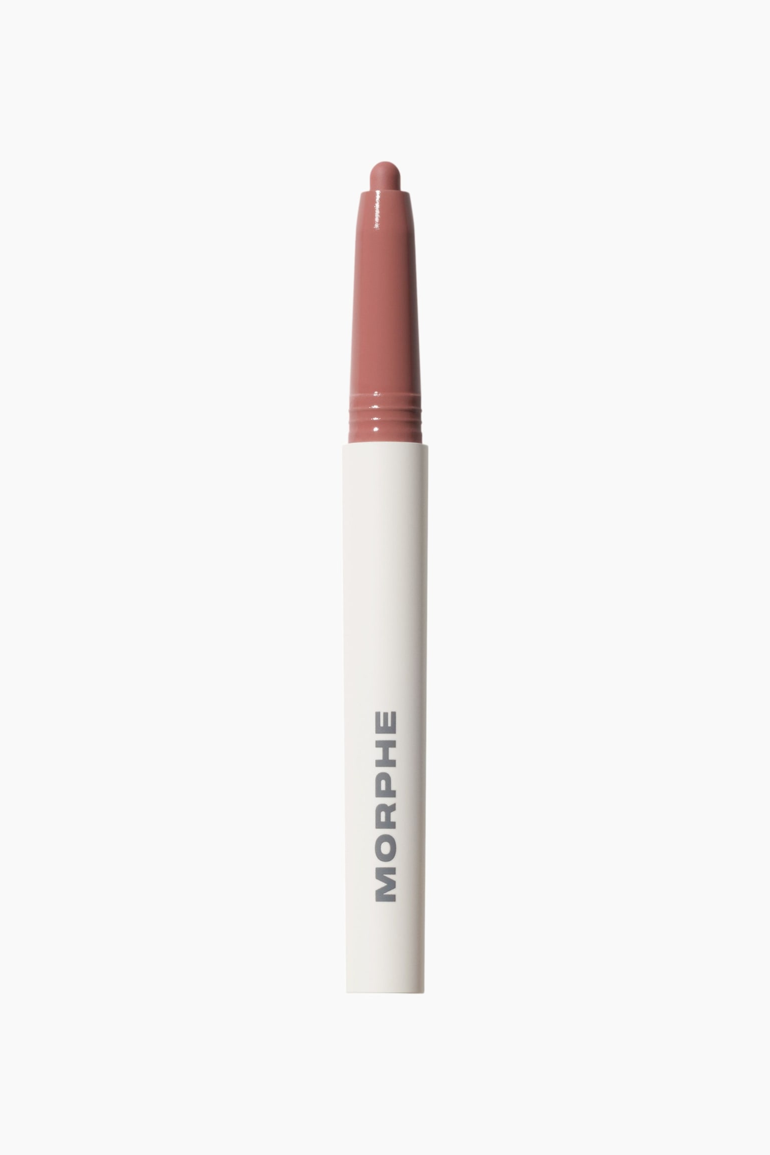 Sculptwear Signature Lip Pencil on pystyasennossa, ja siinä näkyy valkoinen sylinterimäinen runko, jossa brändin nimi âMORPHEâ on painettu pystysuunnassa harmaalla. Pölyisen ruusun sävyinen yläosa jatkuu rungosta ylöspäin ja kapenee saman sävyiseen pyöristettyyn, esillä olevaan kärkeen.
