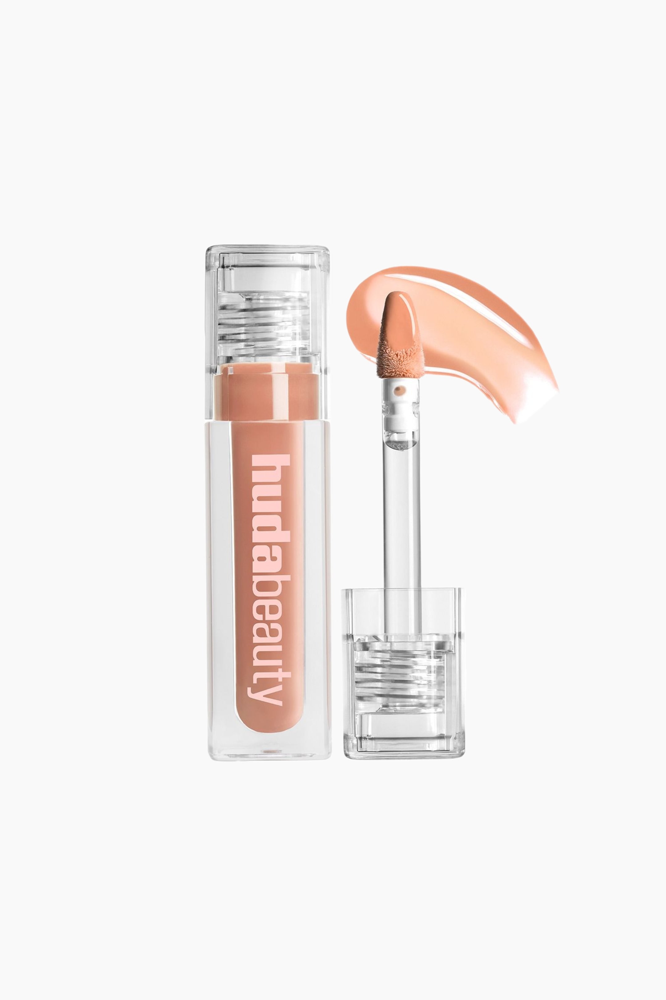 Visa större bild: En klar Huda Beauty läppglansförpackning står upprätt och visar upp sitt persikofärgade nude-innehåll och vertikala 'hudabeauty'-märkning. Dess applikator med hjorthov är utdragen och täckt med glans, medan ett virvlat prov av produkten visar dess färg och textur i närheten.