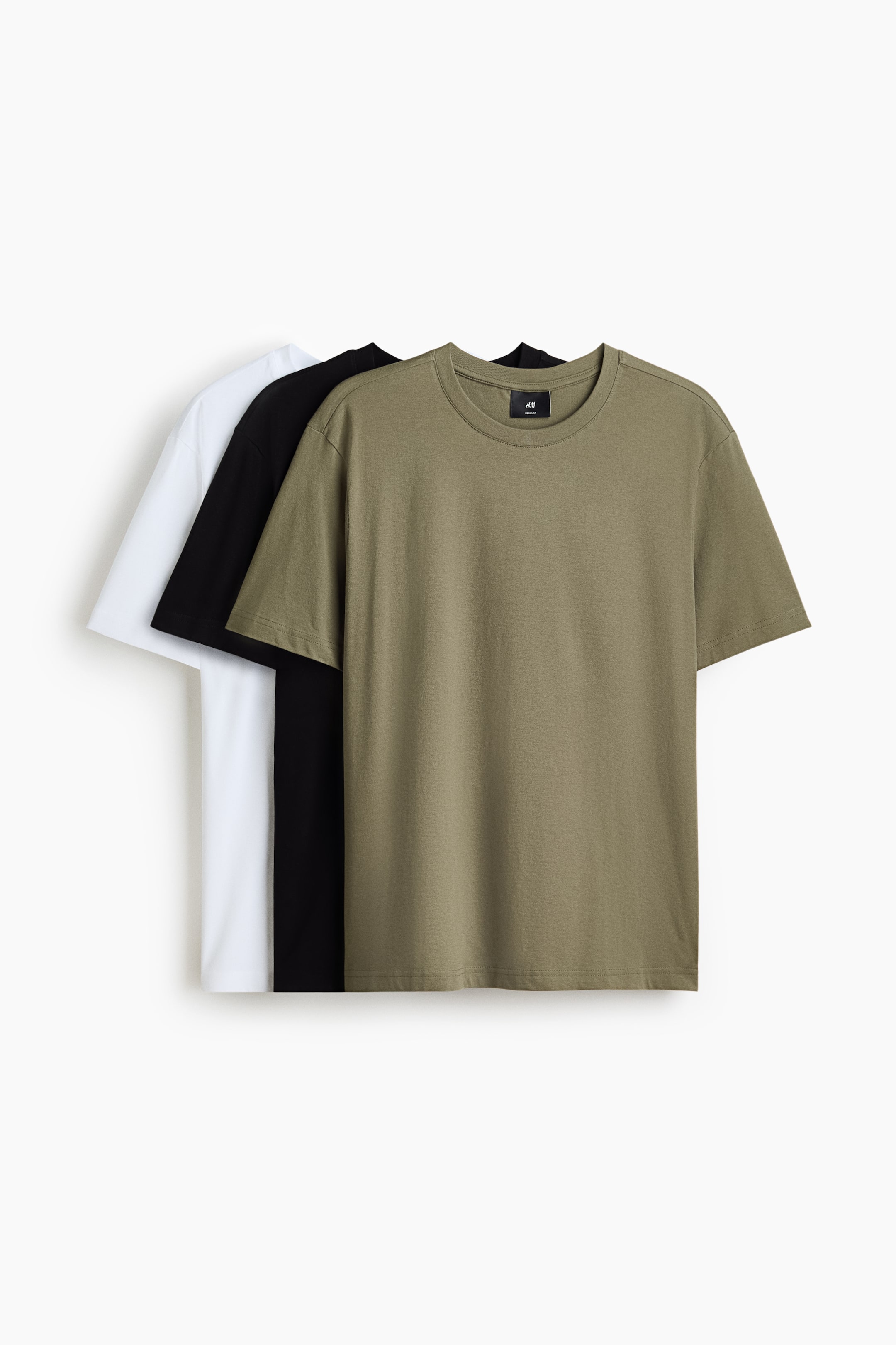 Visa större bild: Tre t-shirts visas med sina framsidor, lager från olivgrön i förgrunden till svart och vit bakom. Varje t-shirt har en rund, ribbad halsringning och en rak skuren nederkant, vilket ger en normal passform.