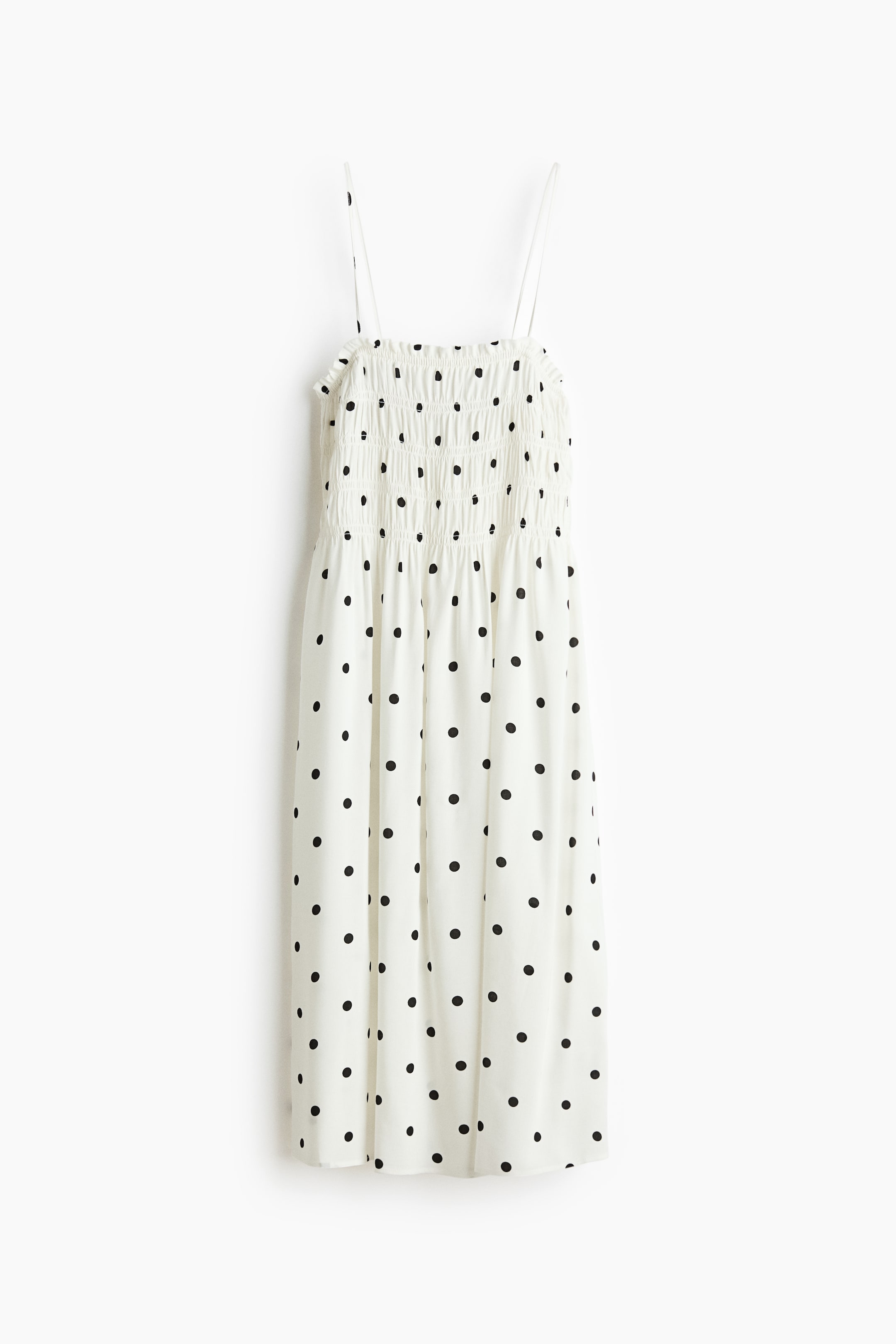 View larger image: The dress features white fabric with black polka dots, presented in a FRONT view. The upper bodice has shirring, and thin spaghetti straps extend from the top.
