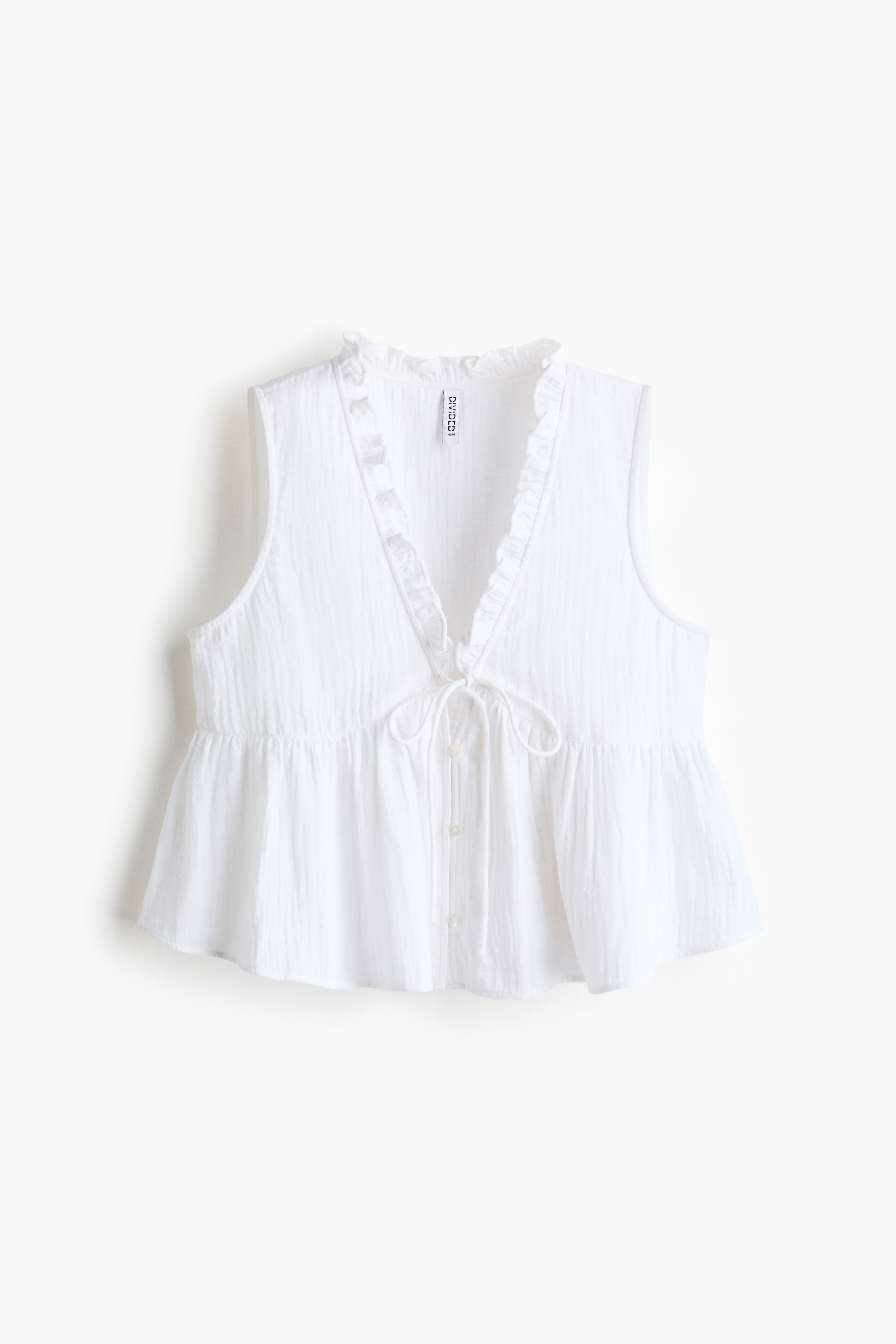 View larger image: A white sleeveless top is shown from the FRONT, featuring a V-neckline with ruffled trim and a crinkled texture. A drawstring is tied at the front, above a gathered peplum hem and a partial button placket.