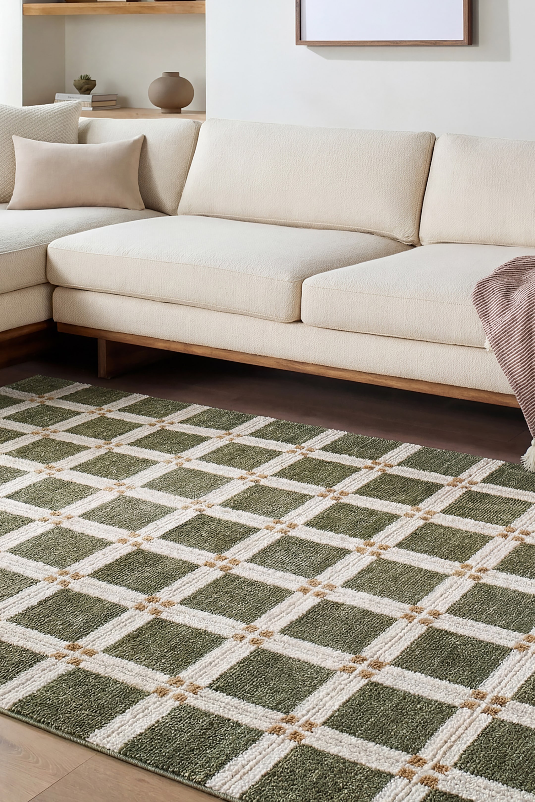 View larger image: An area rug features a green and cream windowpane grid pattern with raised, textured off-white lines. Small tan tufted accents detail the intersections of the grid, creating a structured geometric design shown from an angled perspective.