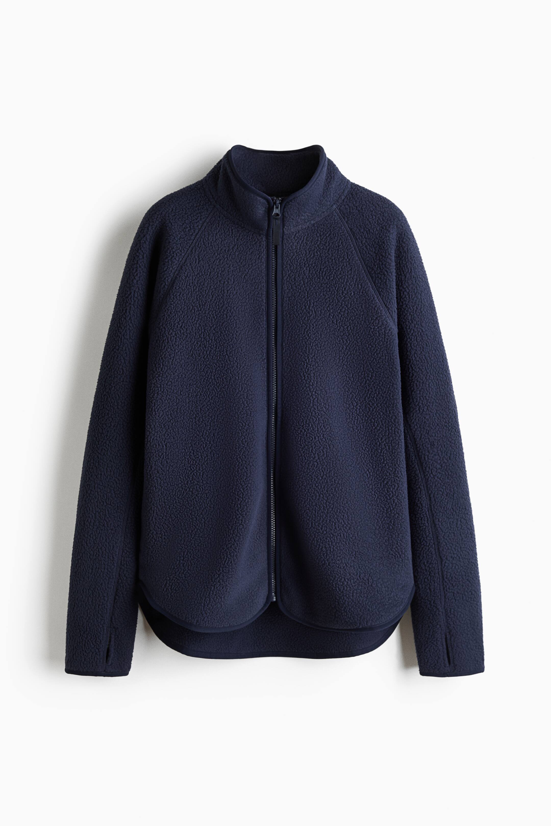 Se større billede: En marineblå teddy fleece-sportjakke hænger fladt og viser for-ansigtet, med opretstående krave og en gennemgående lynlås midt foran. Den har også raglanærmer med elastiske manchetter og tommelfingerhuller, sidelommer samt en afrundet kant med elastisk binding.