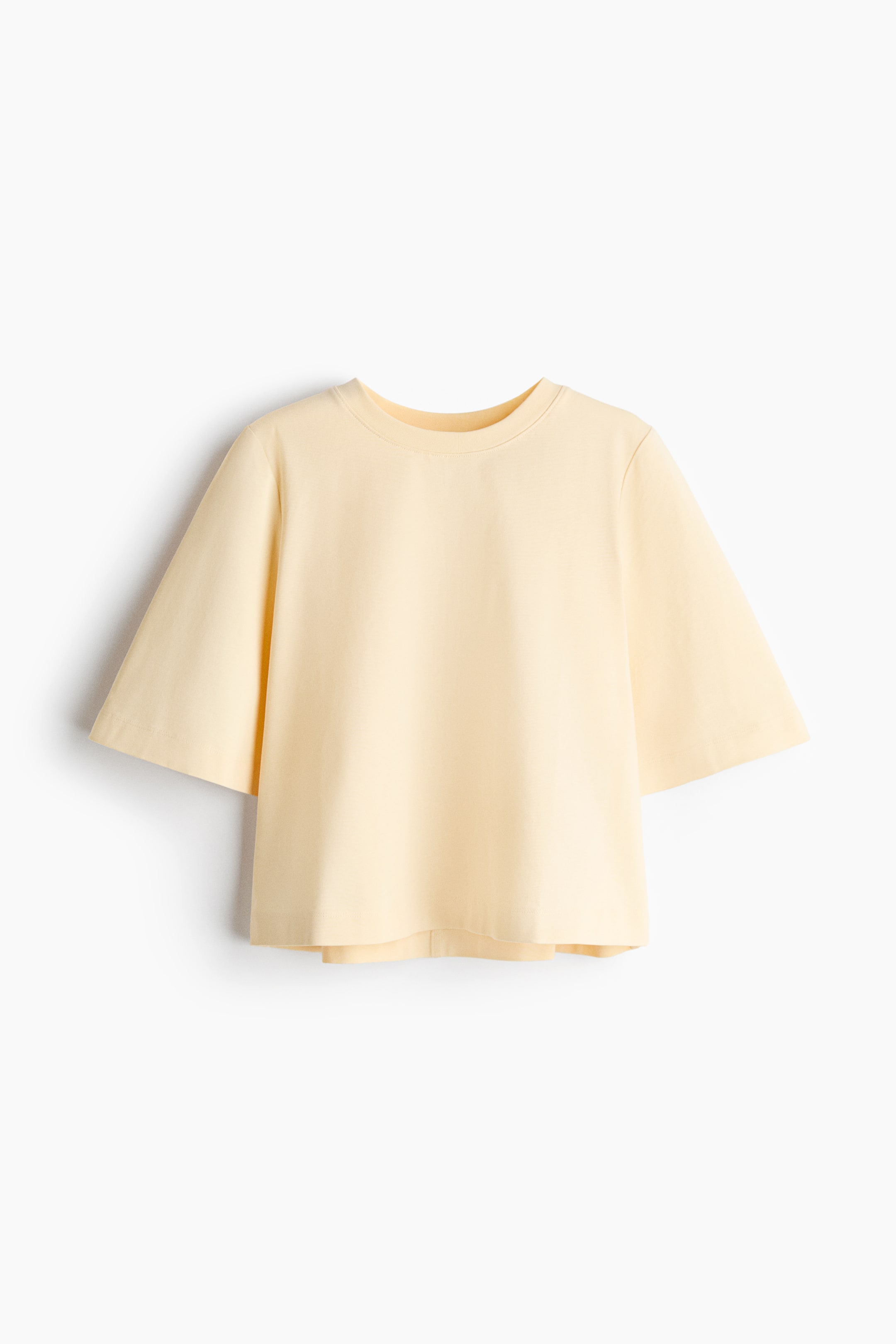 Ver imagen más grande: Una camiseta de color amarillo pálido se presenta en vista frontal, con cuello redondo y mangas cortas y anchas con puños doblados, y un dobladillo recto.