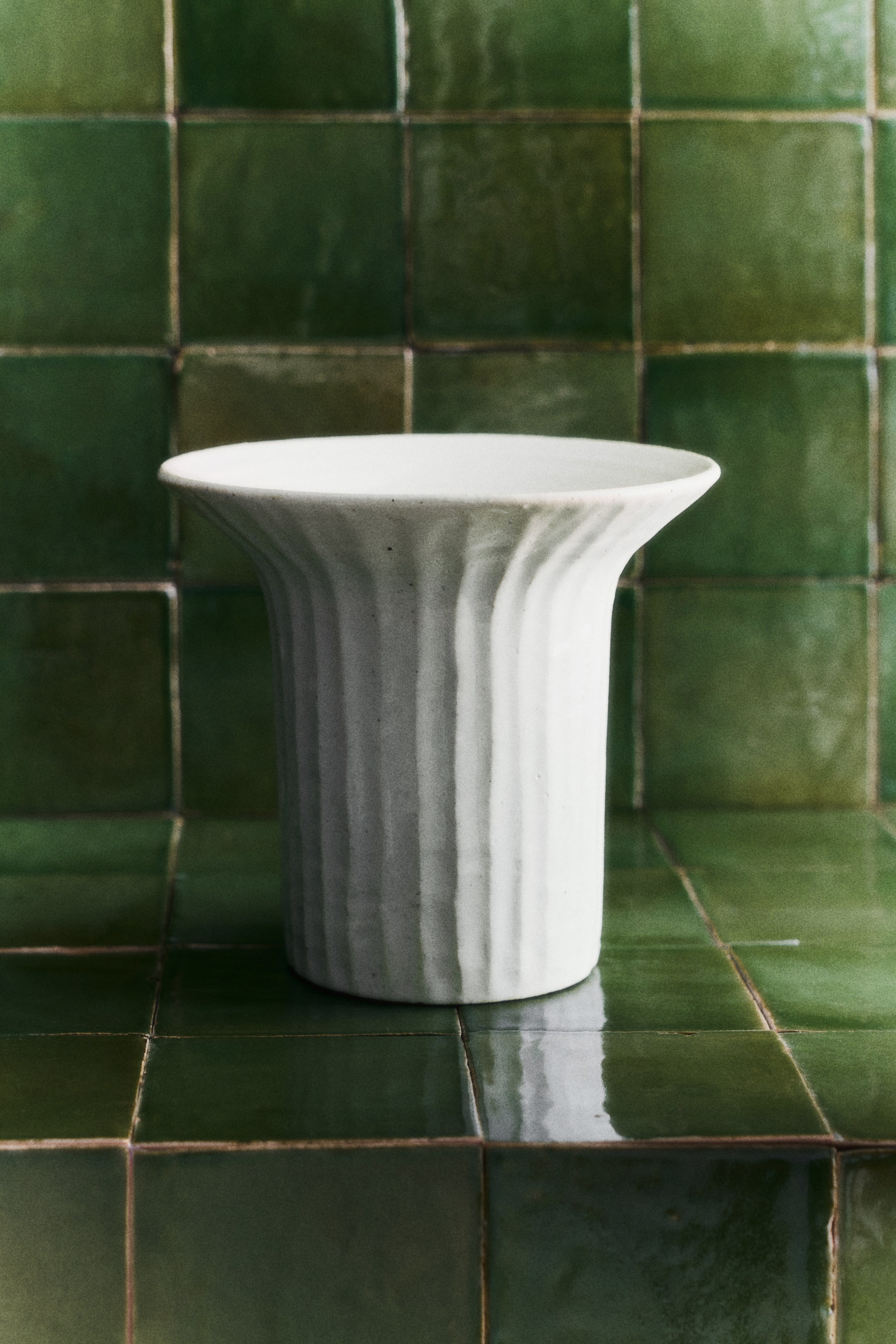 Voir une image plus grande: Un vase en grès présente un bord évasé et un motif ondulé vertical sculpté à la main sur son corps. Il est fini avec un glaçage brillant.