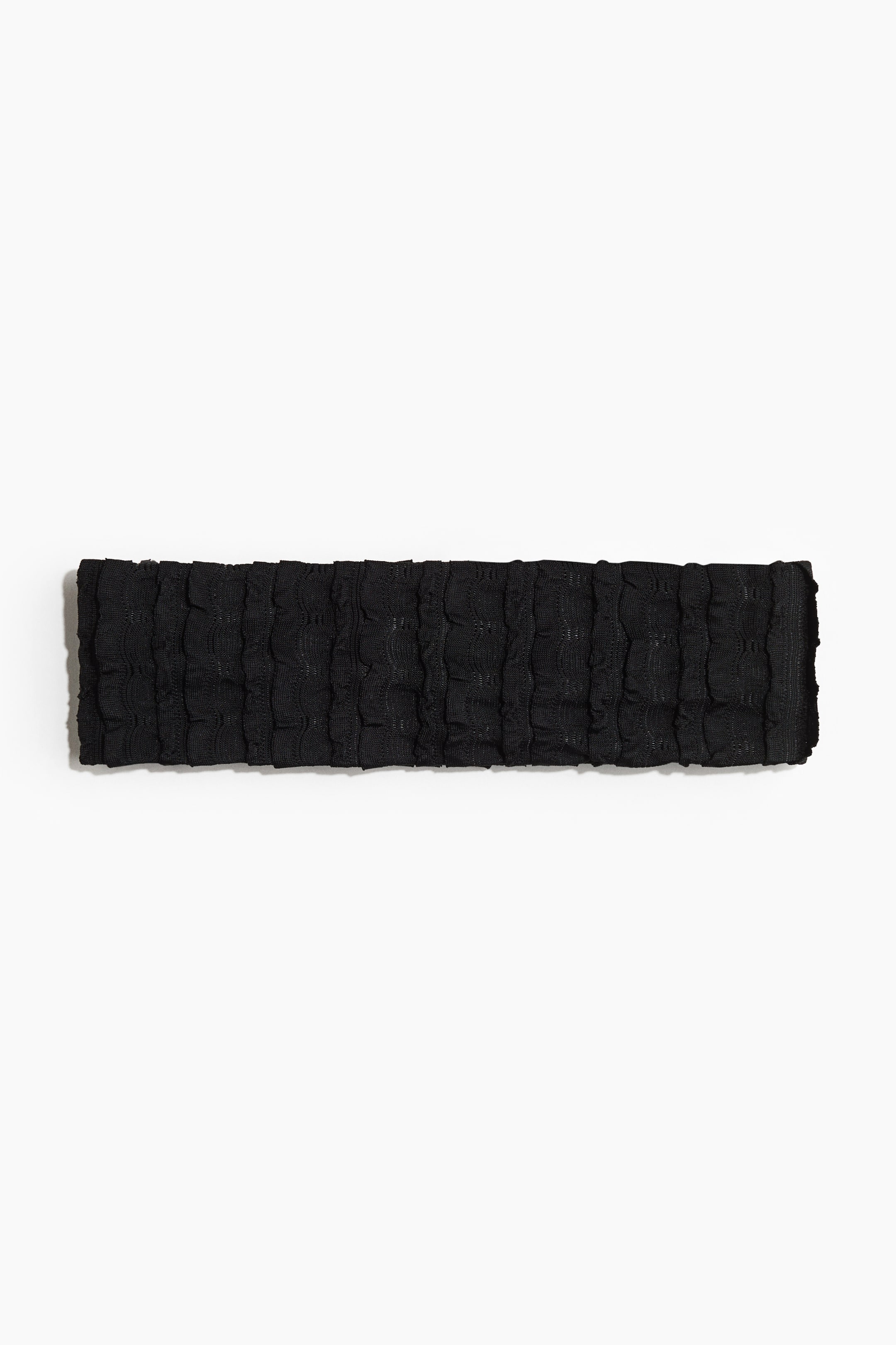 Voir une image plus grande: Un large bandeau noir élastique est présenté à plat, fabriqué dans un matériau en jersey texturé avec des volants verticaux proéminents.