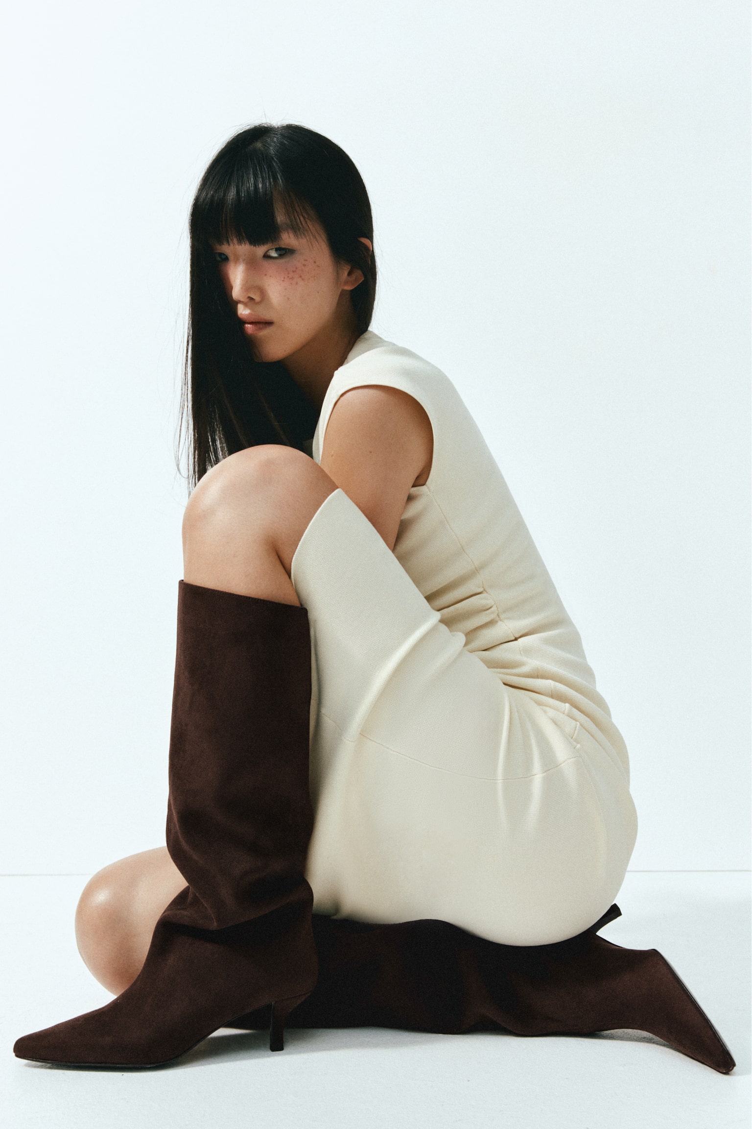 A dark brown suede boot showcases a tall shaft, a pointed square toe, and a slender kitten heel. - 1