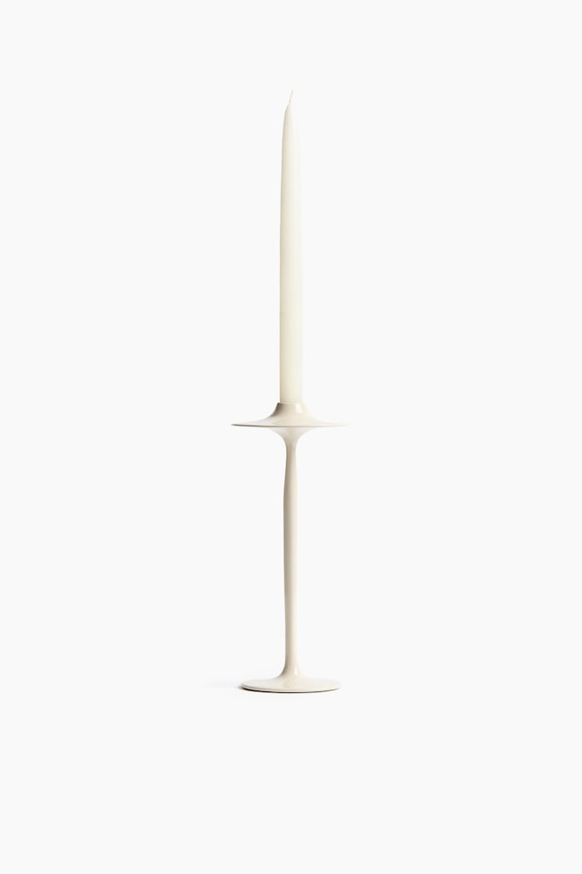 Un bougeoir beige clair tient fermement une bougie effilée blanc crème. Le bougeoir forme une tige élancée qui s'élargit en un plat circulaire à son sommet et une base circulaire plate à son extrémité inférieure. - 1