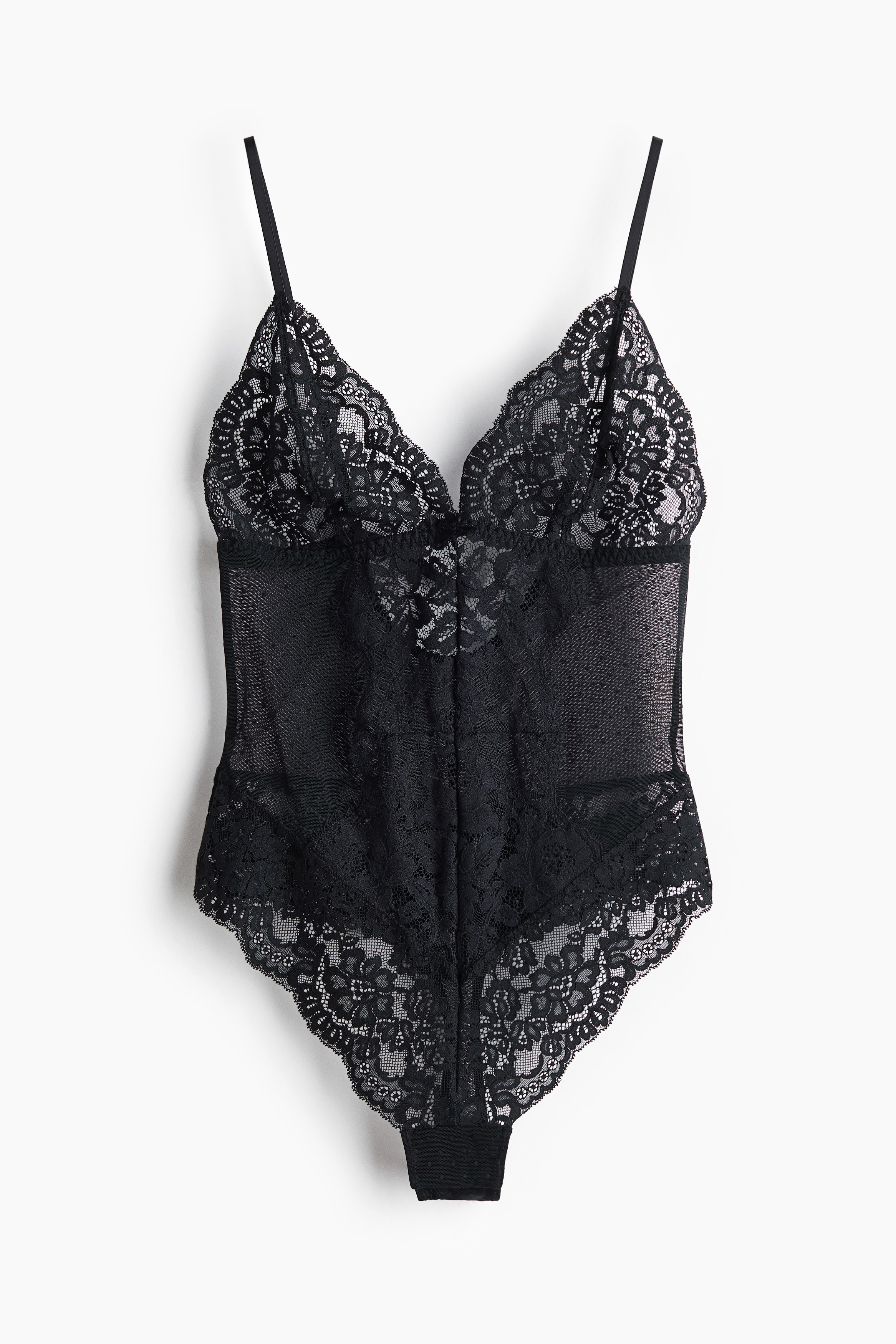 A black V-neck bodysuit in sheer lace and mesh is being worn by the model, who is standing with arms raised overhead. The bodysuit features unlined lace cups, sheer patterned side panels, and thin adjustable shoulder straps.