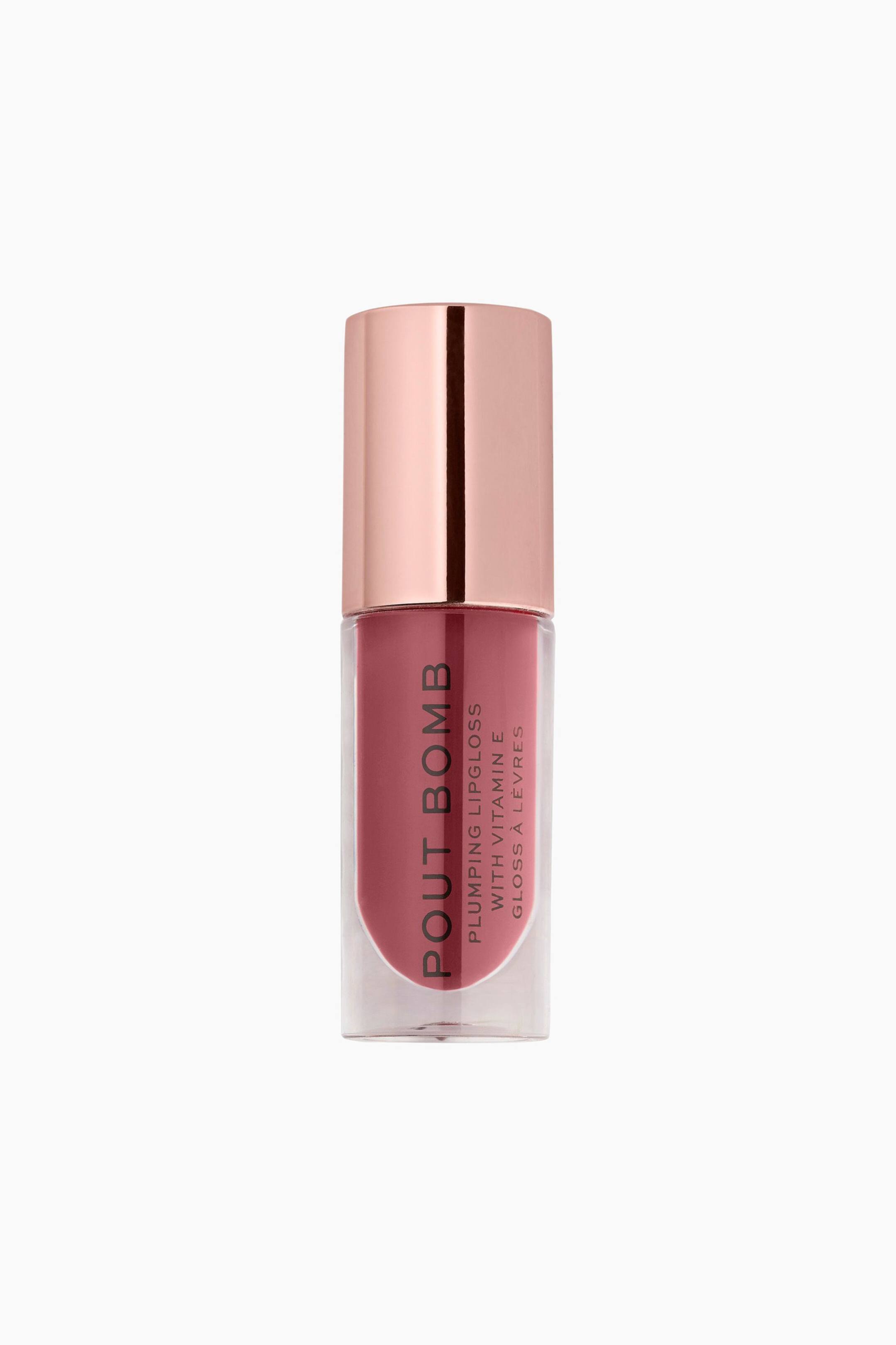 Größeres Bild ansehen: Ein Tuben-Lipgloss von Pout Bomb mit aufpolsternder Wirkung steht aufrecht und zeigt durch seinen klaren, zylindrischen Behälter einen staubigen Roséton. Das Gloss verfügt über einen reflektierenden, roségoldfarbenen Metallverschluss und schwarzen, vertikalen Text auf der Vorderseite.