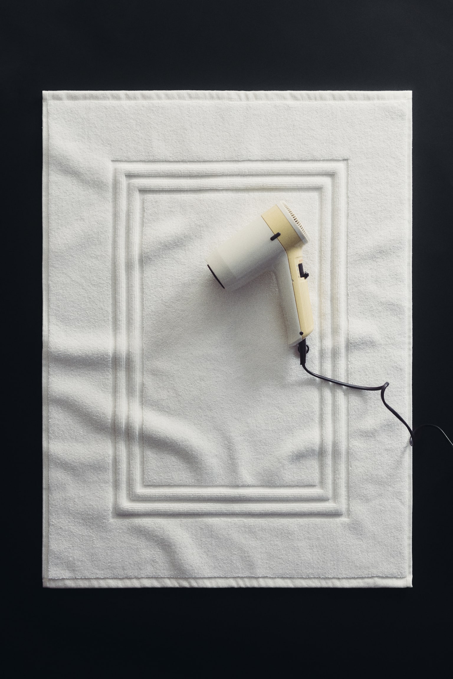 A rectangular white bath mat is displaying a plush texture and a raised, double-lined rectangular border design in its center. - 1