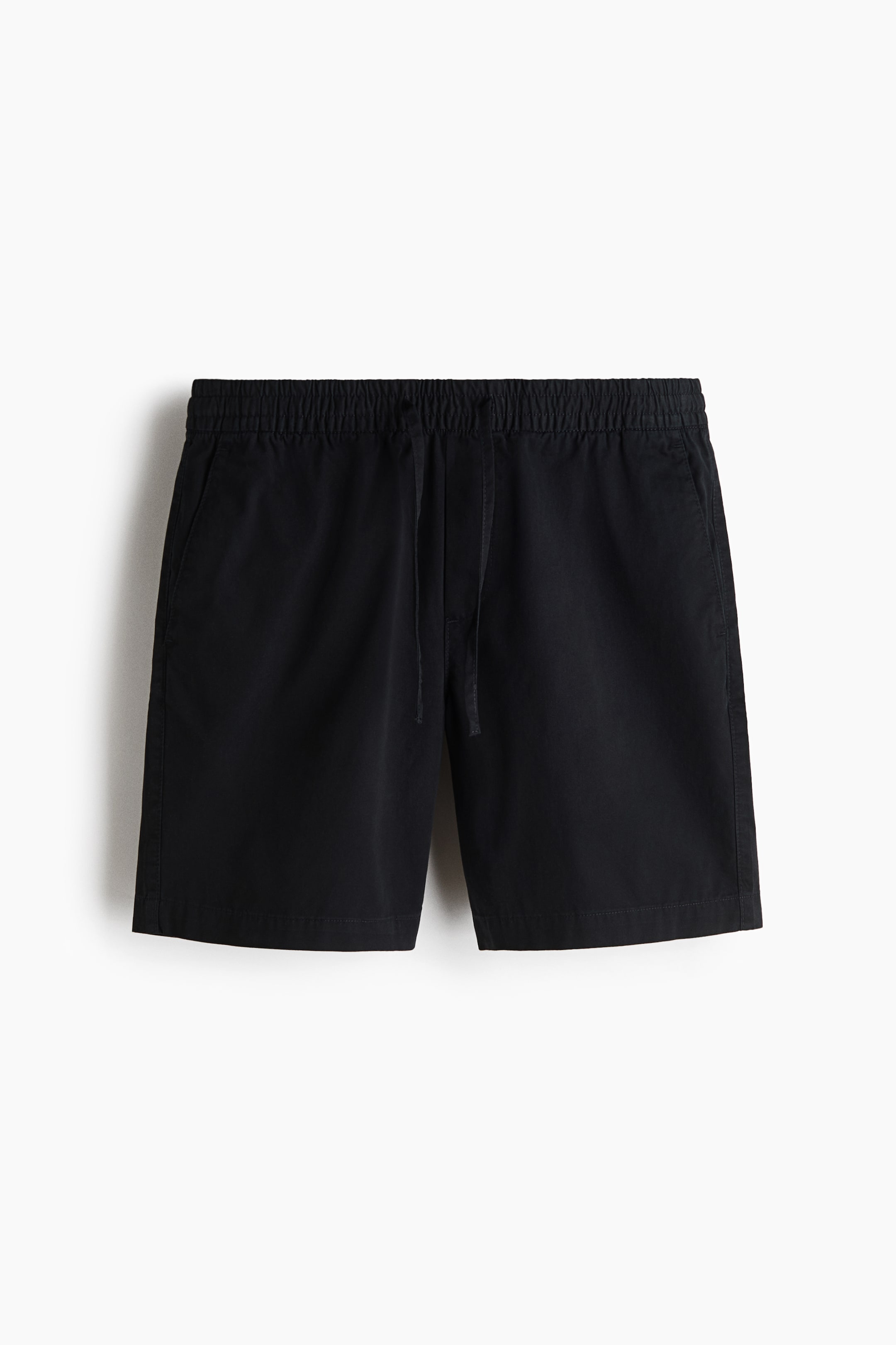 Xem ảnh lớn hơn: Quần short vải twill màu đen được chụp ở góc nhìn chính diện, nổi bật với cạp chun có dây rút. Thiết kế có túi chéo hai bên và đường khóa giả tinh tế, phom dáng thoải mái.