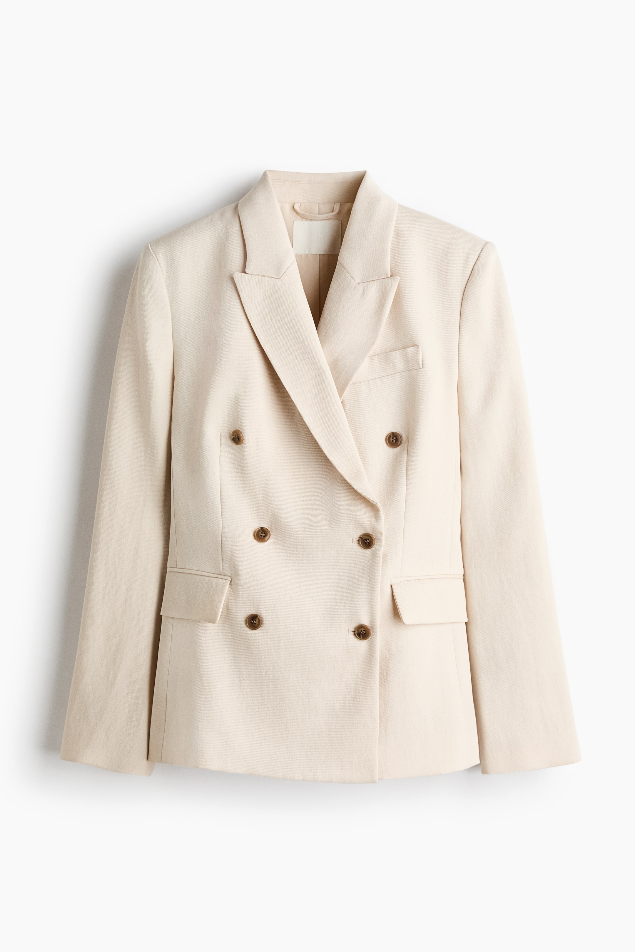 הצגת תמונה גדולה יותר: בלייזר בהיר בצבע בז' כפול חזה מוצג מלפנים, עם דשי חריץ רחבים, שישה כפתורים חומים מסודרים בשתי עמודות, כיס קטן עם פתח על החזה השמאלי ושני כיסים עם מכסה על הירכיים הקדמיות.