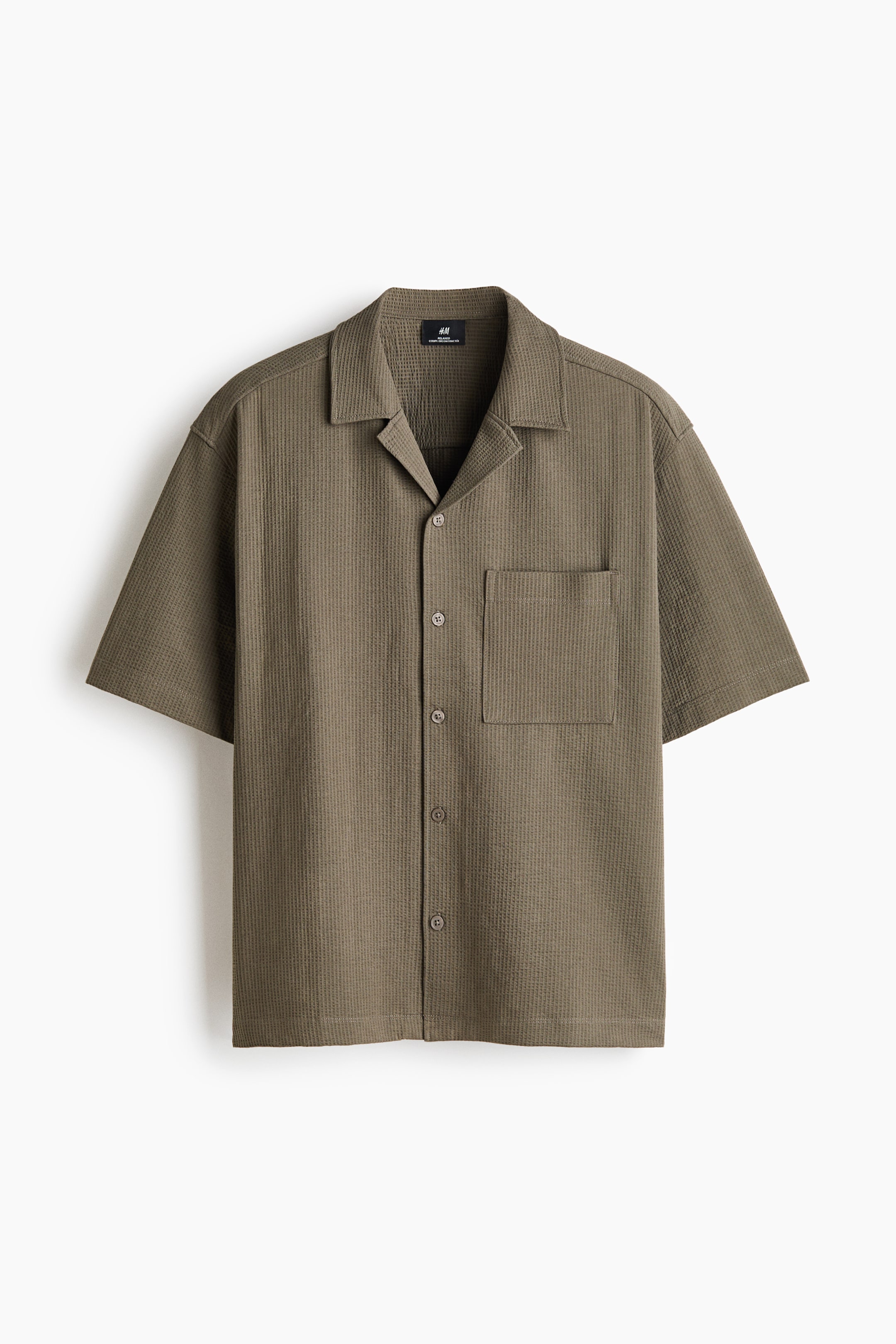 View larger image: A short-sleeve shirt in a waffle-knit cotton-blend fabric is shown from the front in a muted olive-brown colour. It features a relaxed silhouette with a resort collar, a button-down front, a single open chest pocket, and a straight hem.