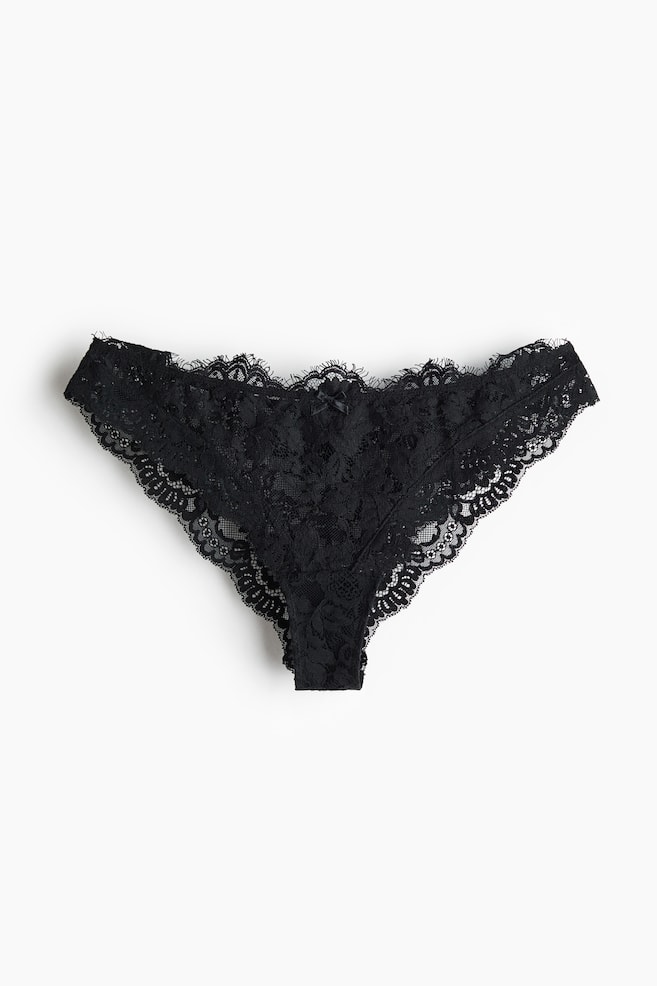 Un string noir en dentelle affiche des motifs floraux délicats et des bords festonnés, avec un petit nÅud en satin noir ornementant le centre de la ceinture. - 1