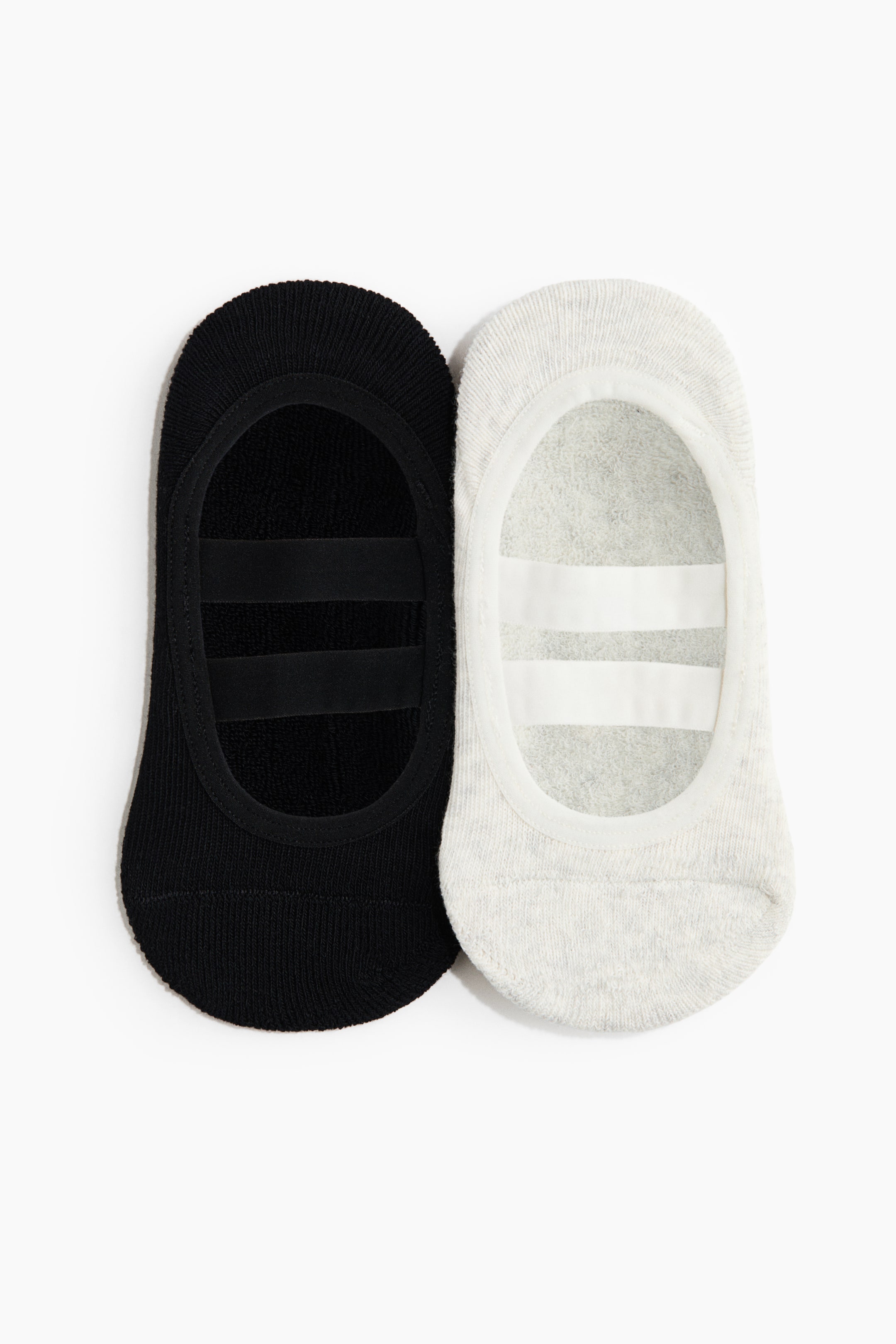 View larger image: Two no-show socks are laid flat, revealing their interior. One sock is black, and the other is light grey, both showcasing two parallel anti-slip strips inside the heel area.