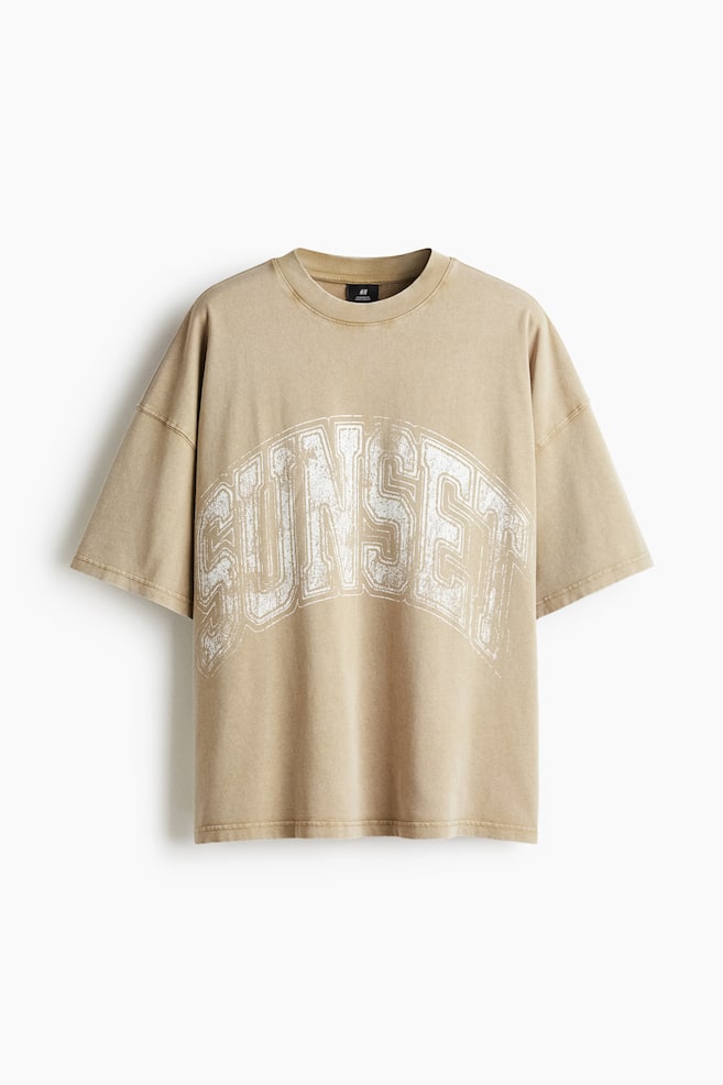 Un t-shirt surdimensionné brun clair et délavé est présenté de FACE, avec des manches courtes et un col rond côtelé. Un graphique blanc usé avec l'inscription « SUNSET » est imprimé en arc sur la poitrine. - 1