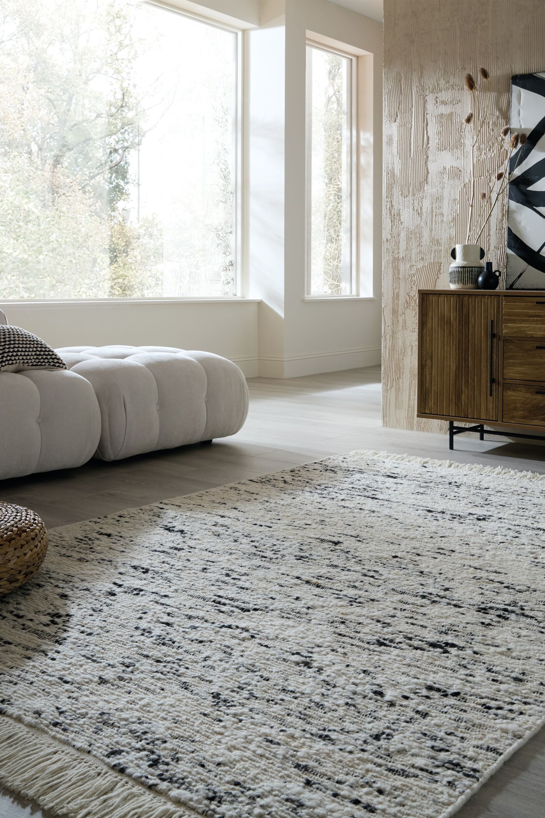 Visualizza immagine più grande: Tappeto caratterizzato da un pelo testurizzato color bianco sporco con un motivo irregolare a strisce grigio scuro e nero. Presenta bordi sfrangiati lungo il lato più vicino all'osservatore.