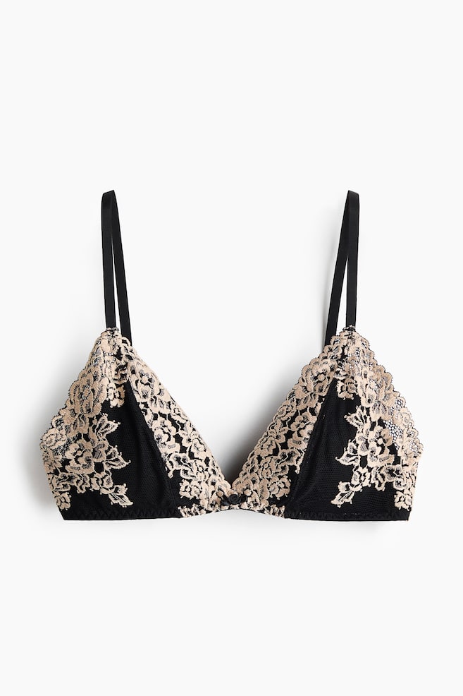A black mesh bra is shown from the front, featuring triangle cups adorned with beige floral lace along the top and outer edges, with thin black adjustable shoulder straps and a small black button at the centre front. - 1