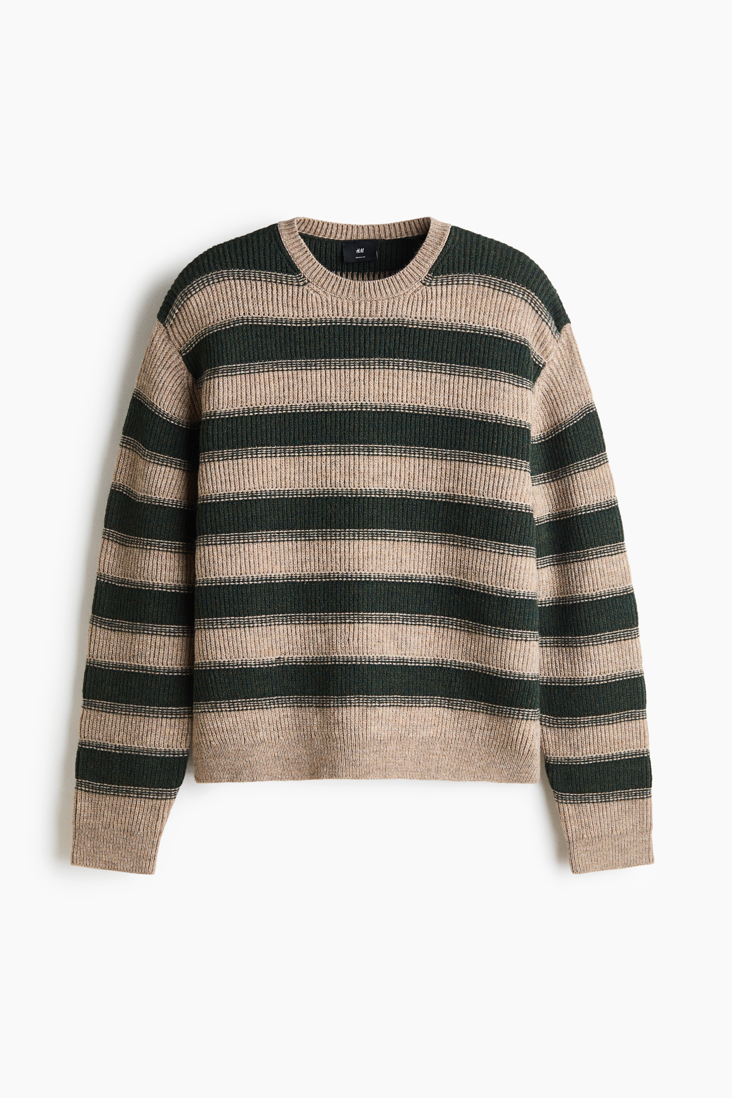 Un maglione a coste a righe in beige e verde scuro indossato dalla modella, caratterizzato da girocollo, spalle scese e finiture a coste su polsini e orlo. Il maglione è abbinato a jeans blu scuro, con la modella che posa una mano vicino alla tasca posteriore.