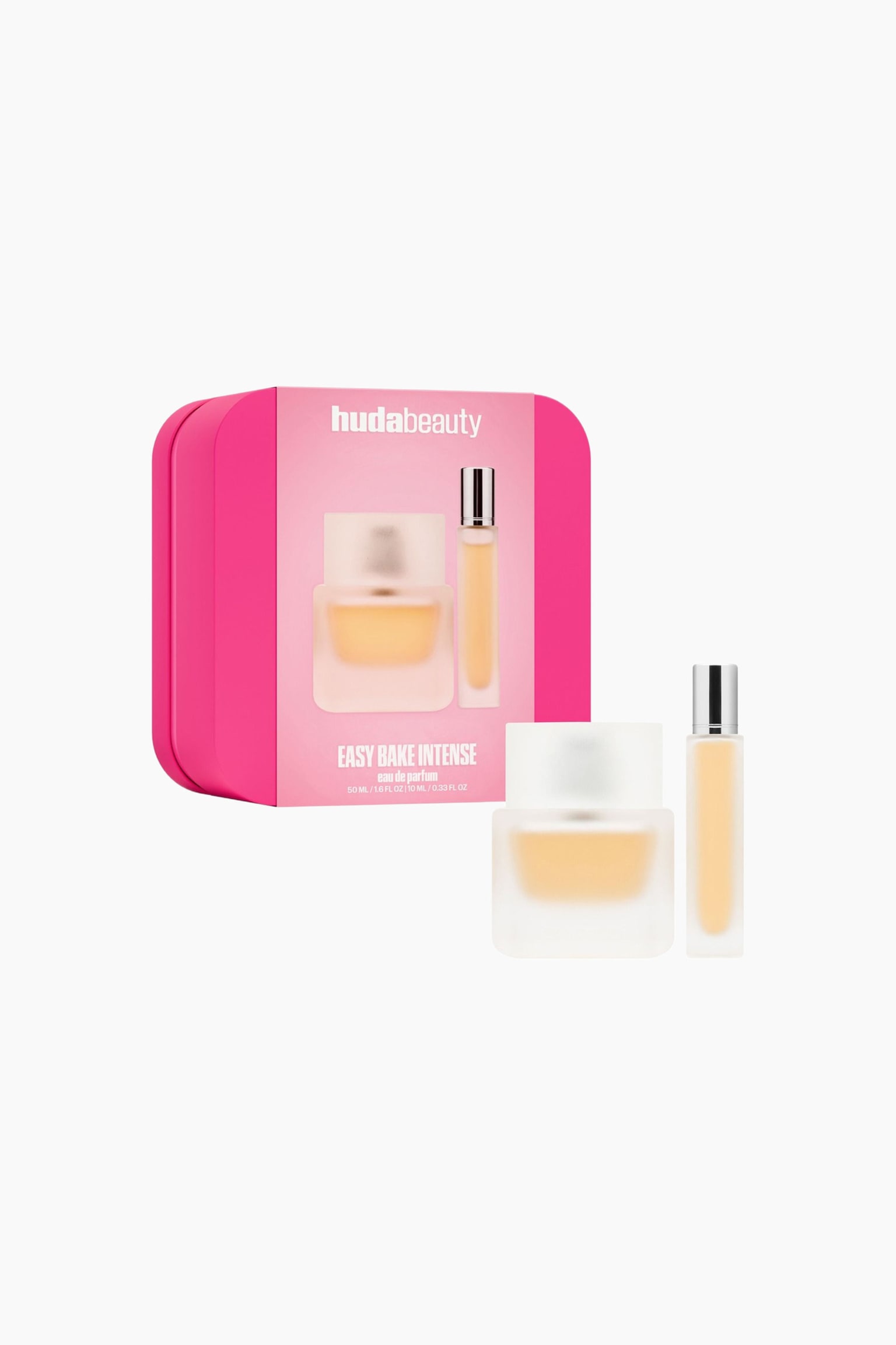 Settet Easy Bake Intense Fragrance Duo er vist frem med en livlig rosa blikkboks ved siden av en firkantet, frostet parfymeflaske i glass og en slank, sylindrisk reisepumpe. Begge flaskene står oppreist foran boksen og fremhever den lys ferskenfargede væsken gjennom det halvtransparente glasset.