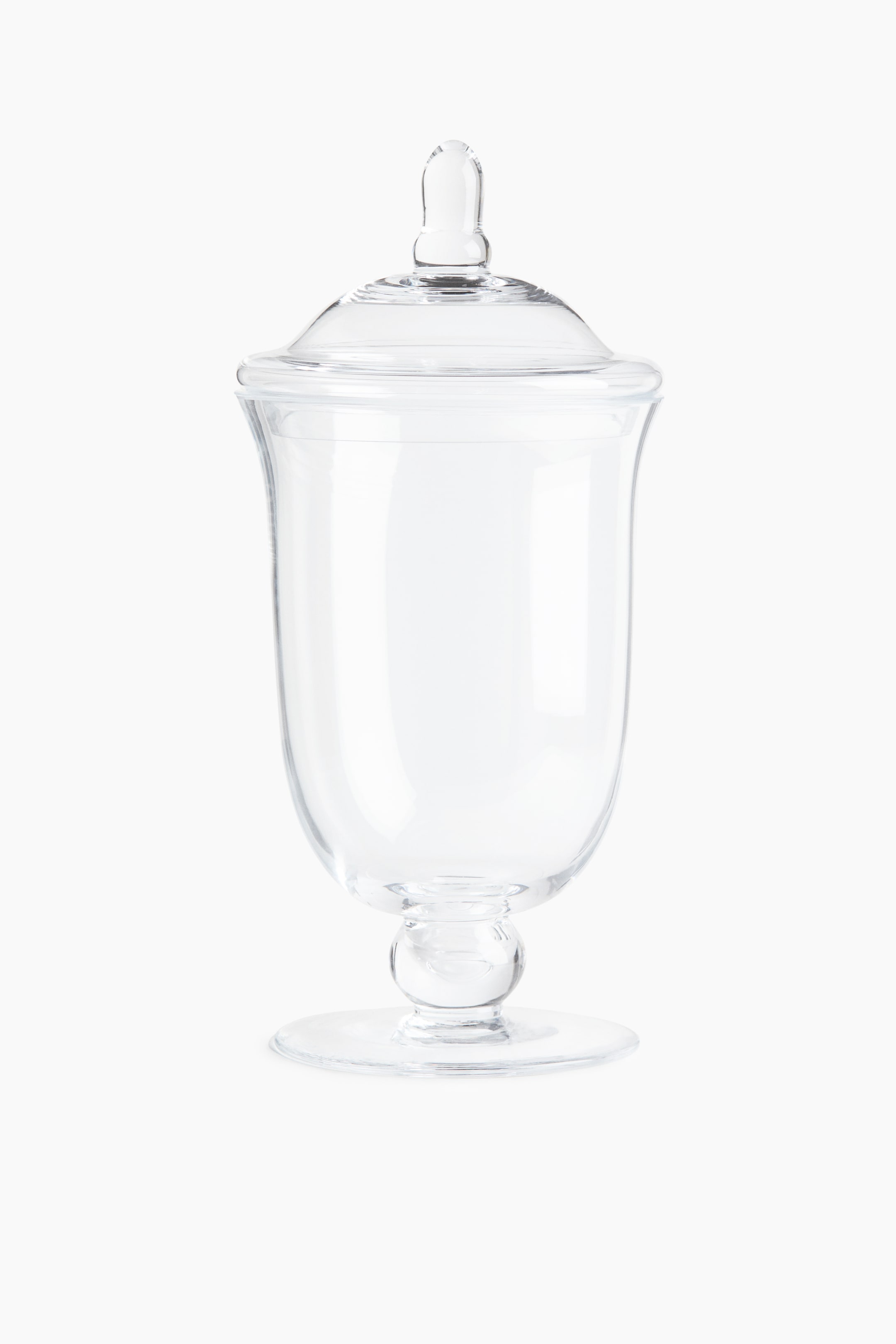 View larger image: A tall footed glass jar is standing upright from a front angle, featuring a gently flared opening and a rounded body supported by a pedestal base with a circular foot. The jar is topped with a matching domed glass lid featuring an elongated knob.