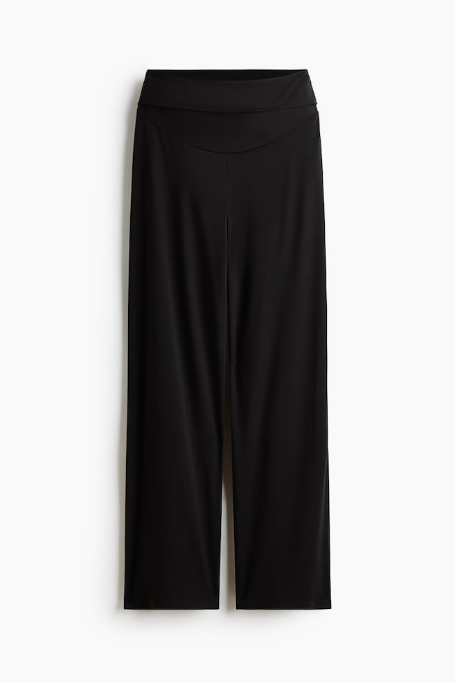 Une paire de pantalons noirs Ã  jambes larges est prÃ©sentÃ©e de face, avec une large ceinture rabattue et une couture d'empiÃ¨cement incurvÃ©e. Le pantalon tombe dans une silhouette dÃ©contractÃ©e Ã  jambes larges. - 1