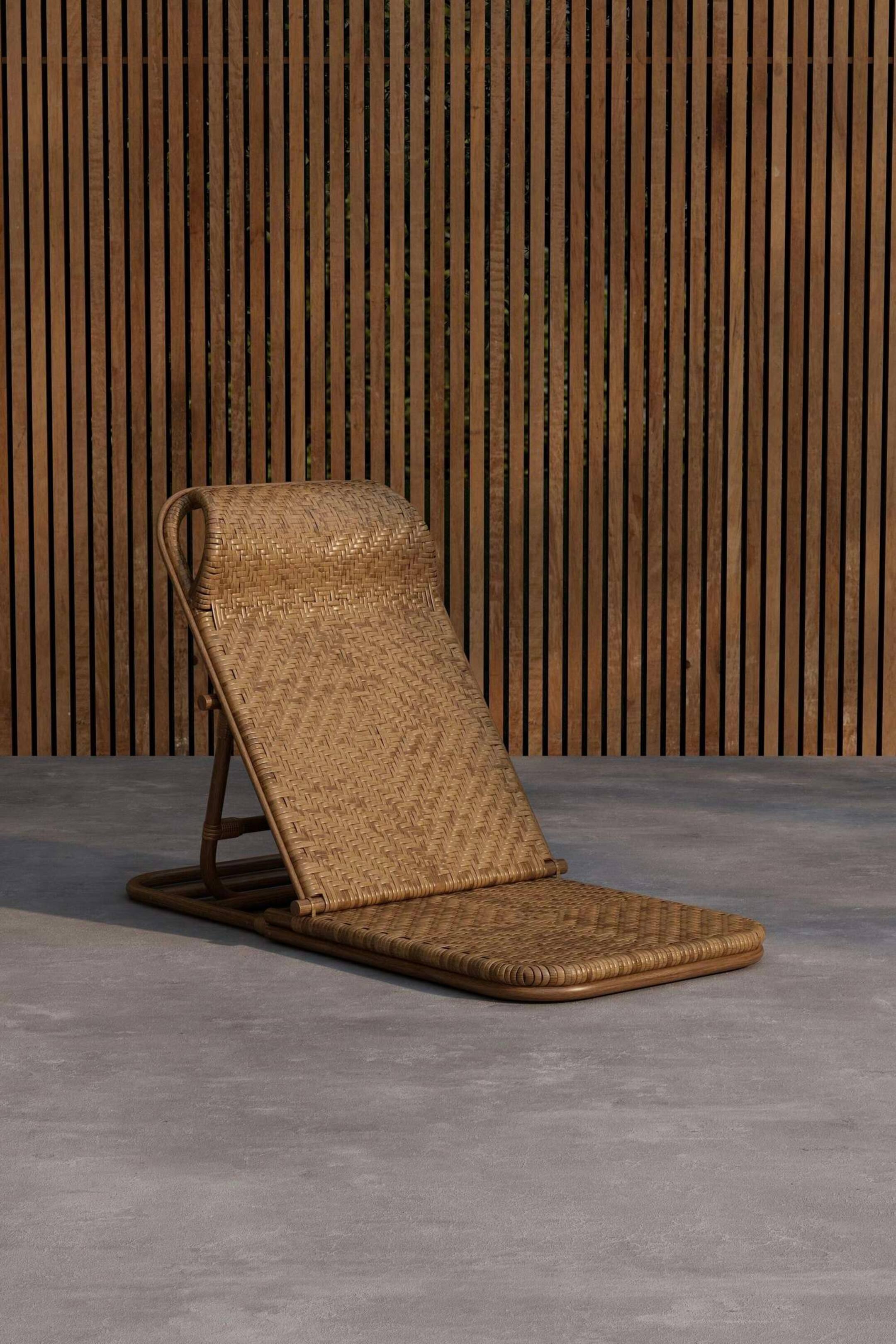 Agrandir l'image: Un fauteuil lounge en osier naturel est incliné de l'avant, montrant un dossier incliné et une assise plate. Les panneaux tissés du fauteuil présentent un motif chevron sur le dossier et un tissage droit sur l'assise.