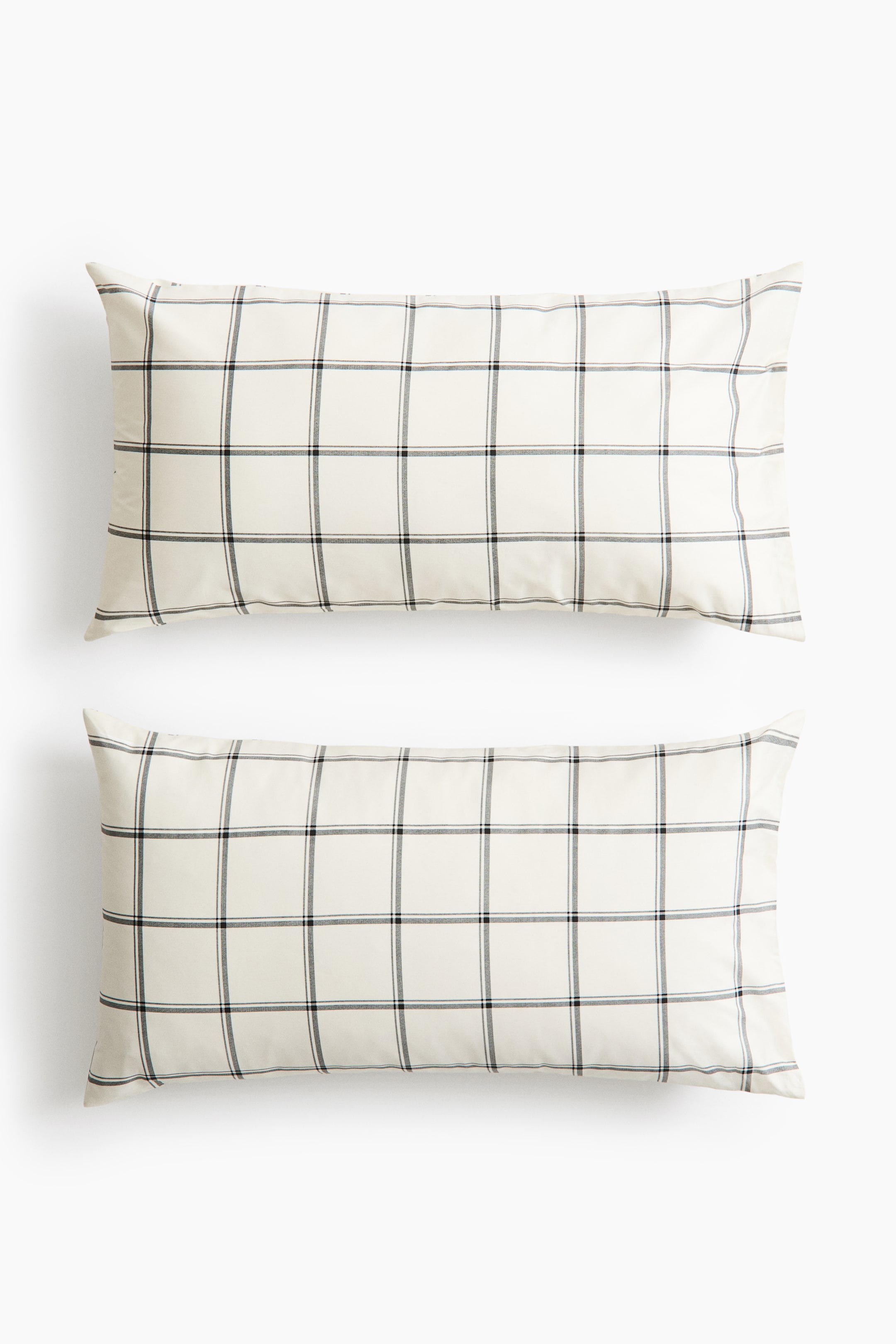 View larger image: Two rectangular sateen pillowcases are positioned facing forward in a vertical arrangement, showcasing an off-white fabric with a dark grey grid pattern. The smooth cotton material displays a subtle sheen across its surface.