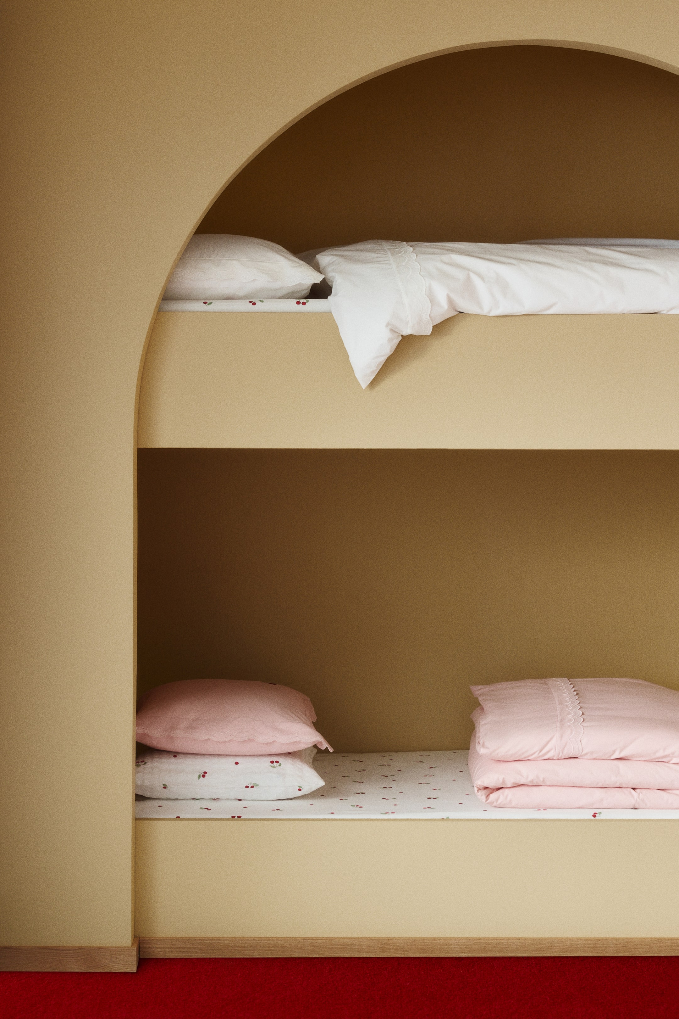 View larger image: A single duvet cover set in soft cotton percale featuring a scalloped trim with tone-on-tone embroidery along the top edge of the duvet cover, visible in both white and pink examples. The matching pink pillowcase displays scalloped, embroidery-detailed edges on its wide border.
