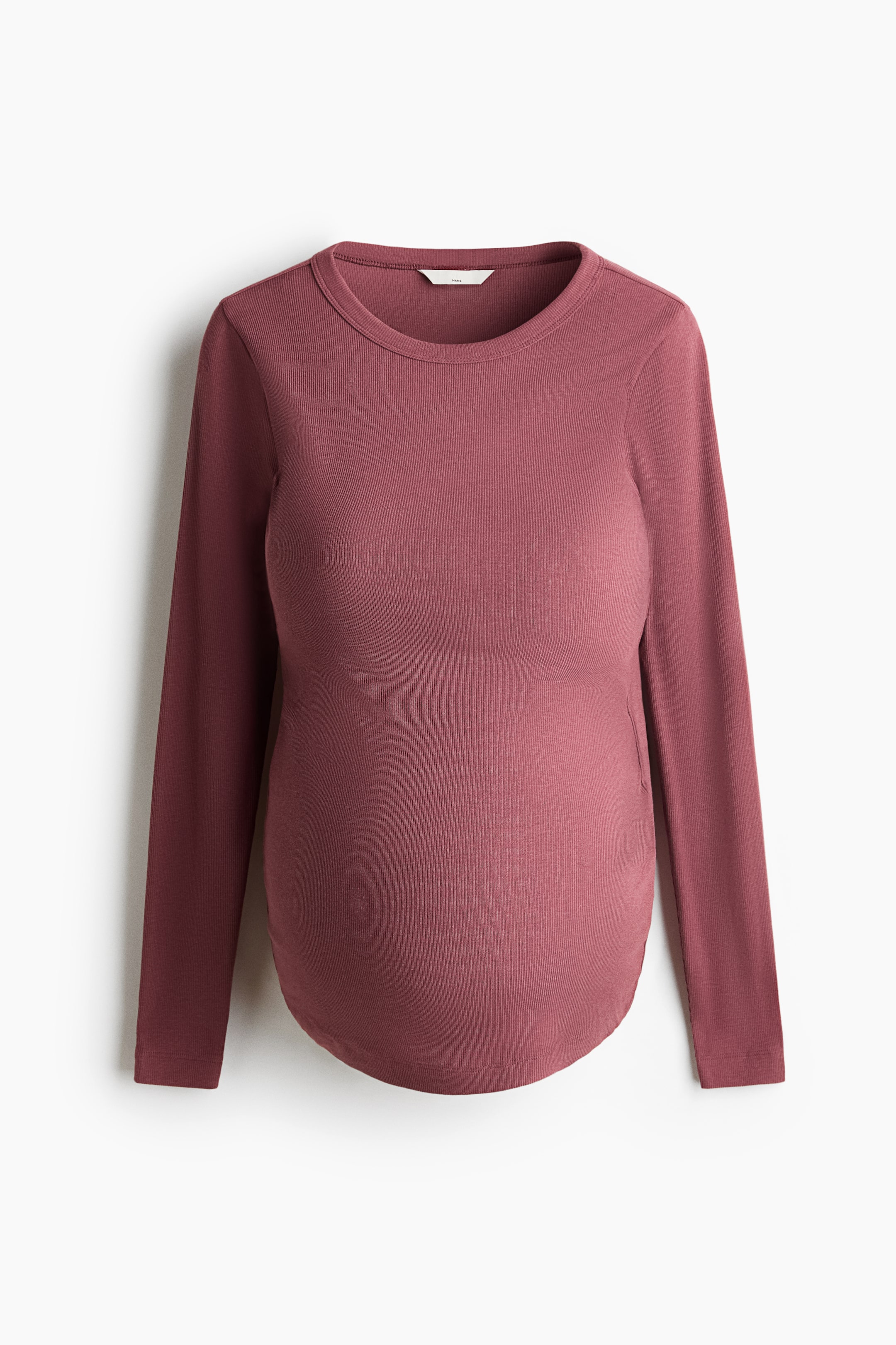 View larger image: A fitted top in deep rose red ribbed jersey is presented from the front, featuring a round neckline and long sleeves. It showcases a design with a rounded hem and subtle gathering on the sides.