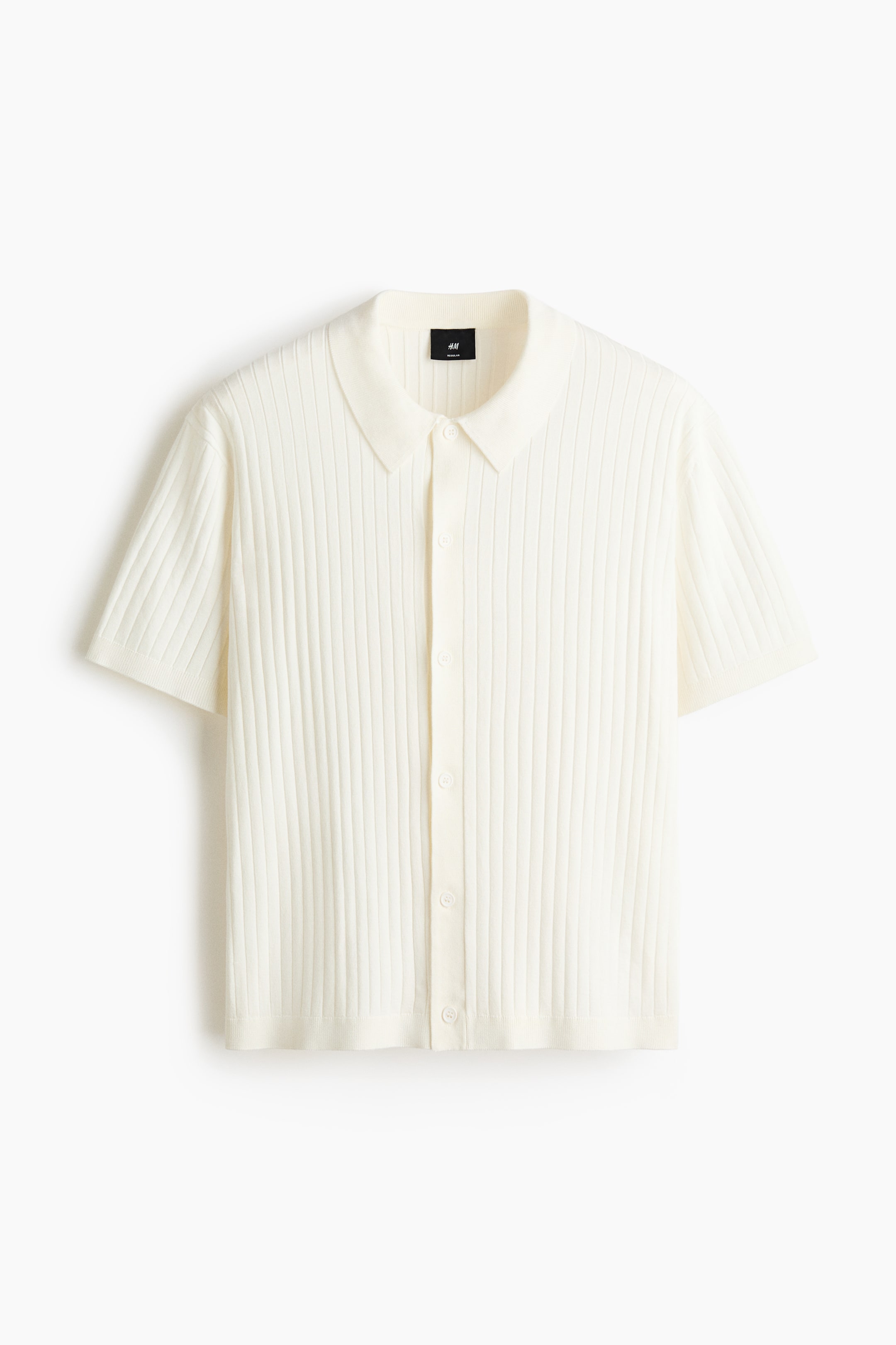 View larger image: A cream-colored polo shirt is presenting its FRONT, featuring a soft, ribbed knit texture. It is displaying a classic collar, a button placket down the front, short sleeves, and a straight-cut hem, offering a regular fit.