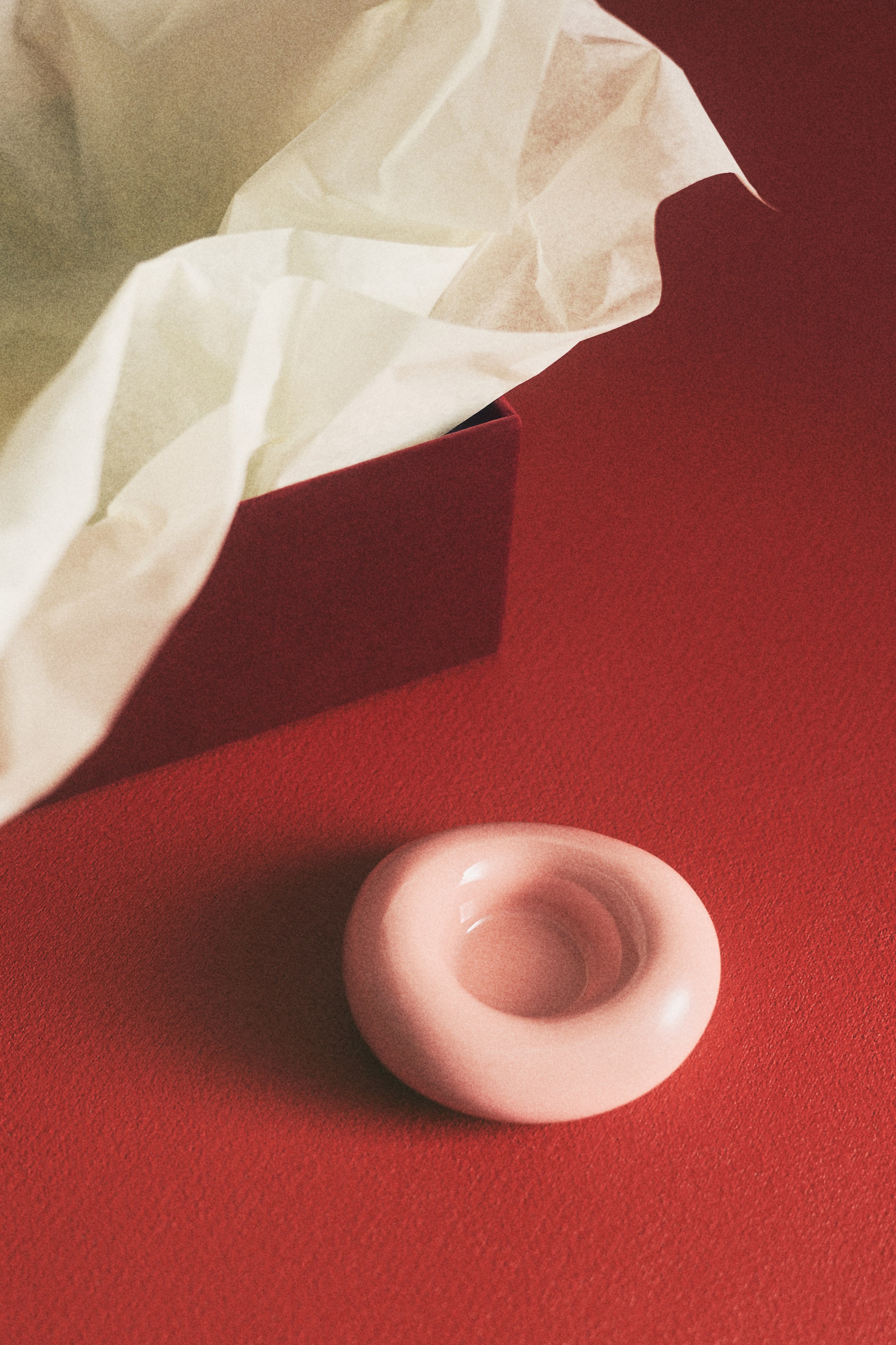 Agrandir l'image: Un objet en forme d'anneau rose pâle repose sur une surface, à la finition lisse et brillante et doté d'une dépression circulaire centrale.