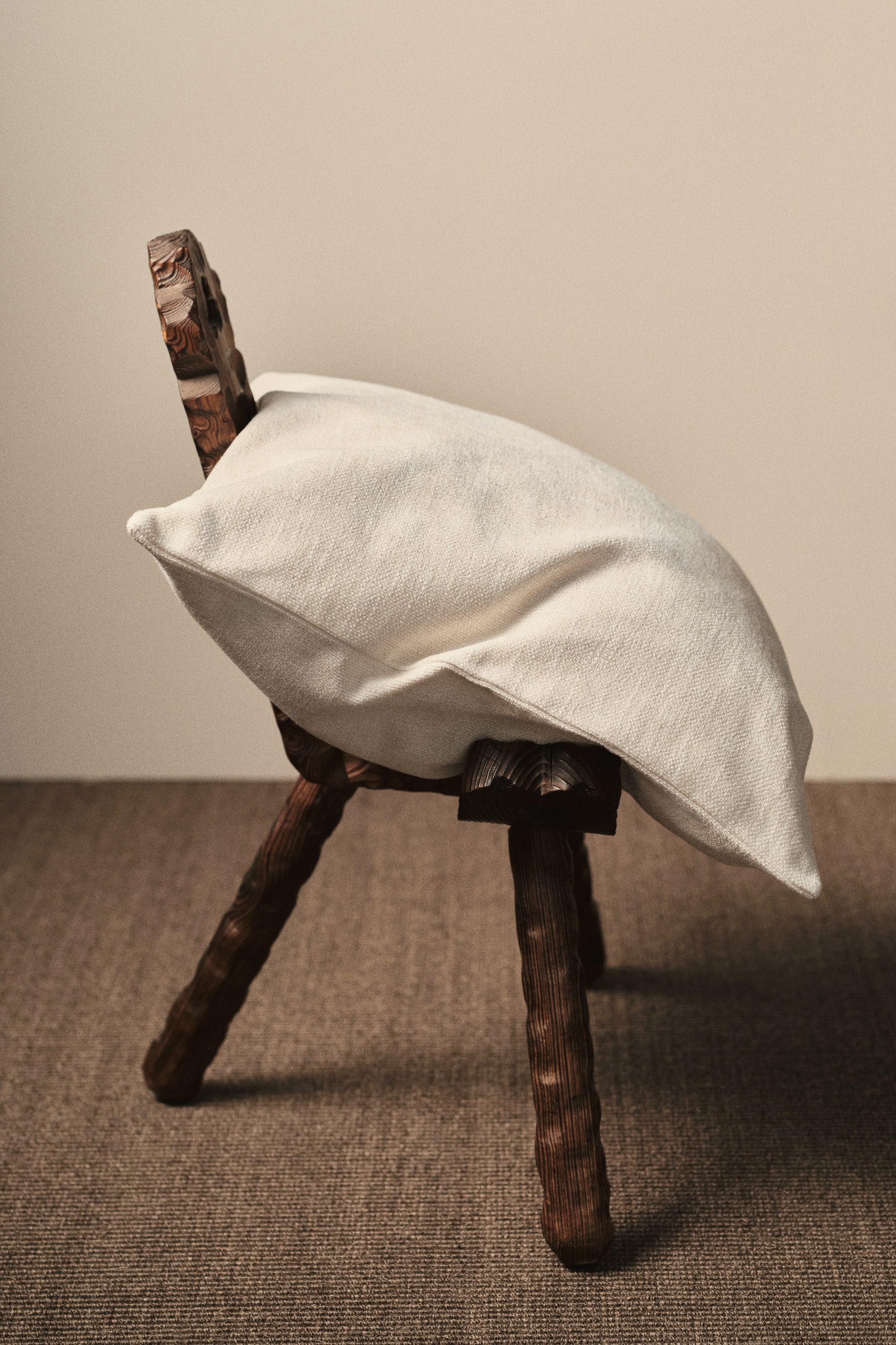 Grotere afbeelding bekijken: Een lichtgekleurde kussenhoes in een zachte chenille weefsel ligt op een stoel, met een rits langs één zijde en toont zijn volle vorm.