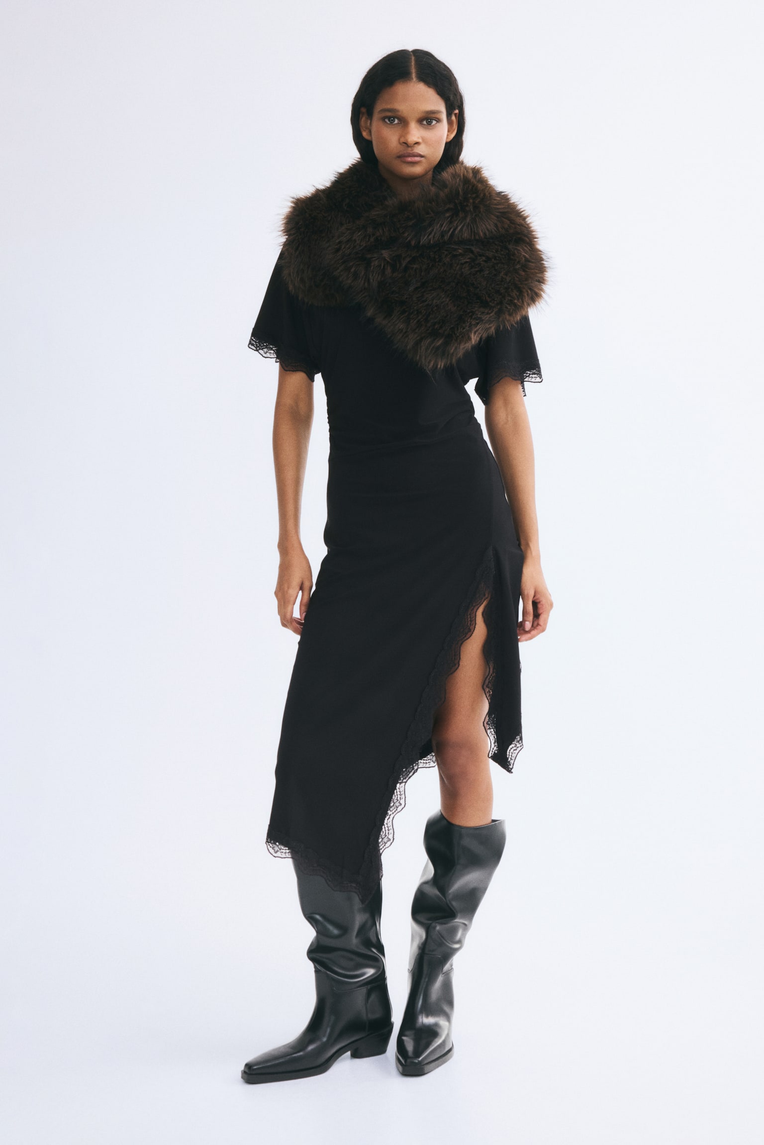 A black dress featuring a round neckline and short sleeves with lace trim. Its asymmetrical hemline is adorned with lace, extending up a visible side slit. - 1