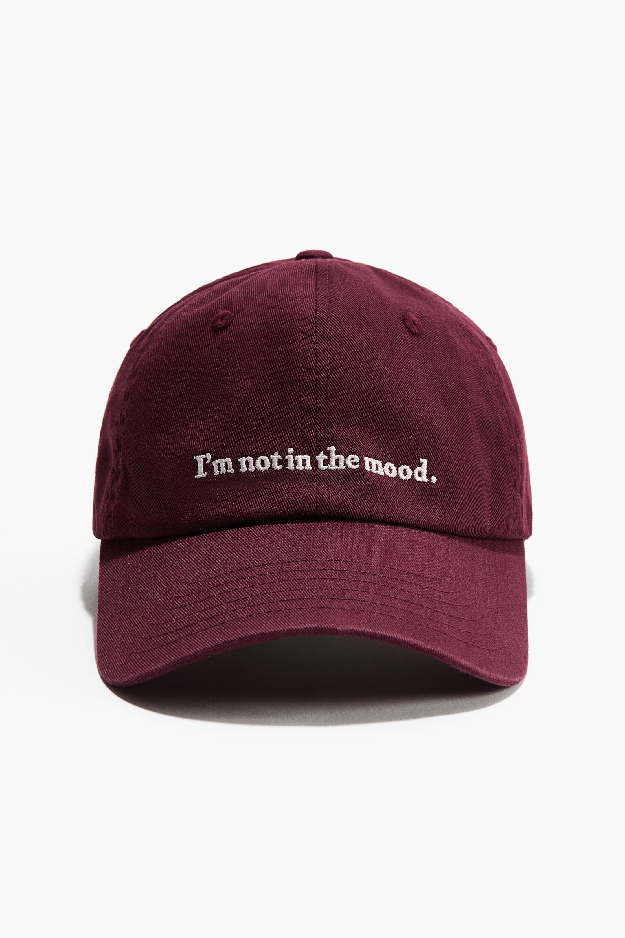 View larger image: A maroon cotton twill cap is facing FRONT, displaying white embroidered text that reads "I'm not in the mood" on its crown. It is featuring a curved brim and subtle embroidered eyelets.