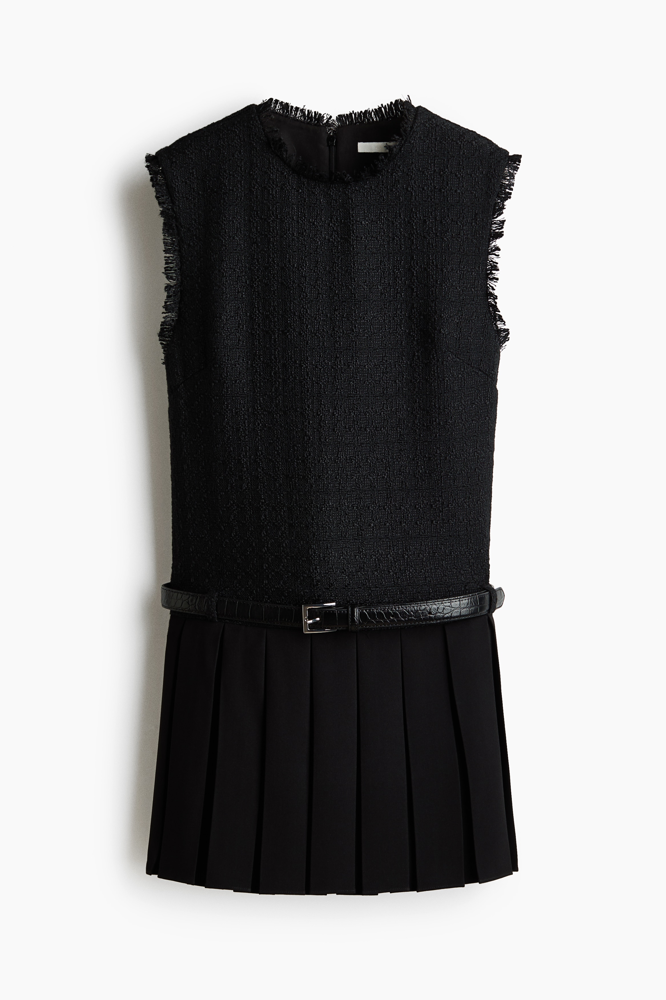 A black, sleeveless, textured top featuring frayed edges at the neckline and armholes is being worn by the model with a matching black pleated mini skirt. A thin black belt with a silver-tone buckle is fastened at the waist of the skirt.