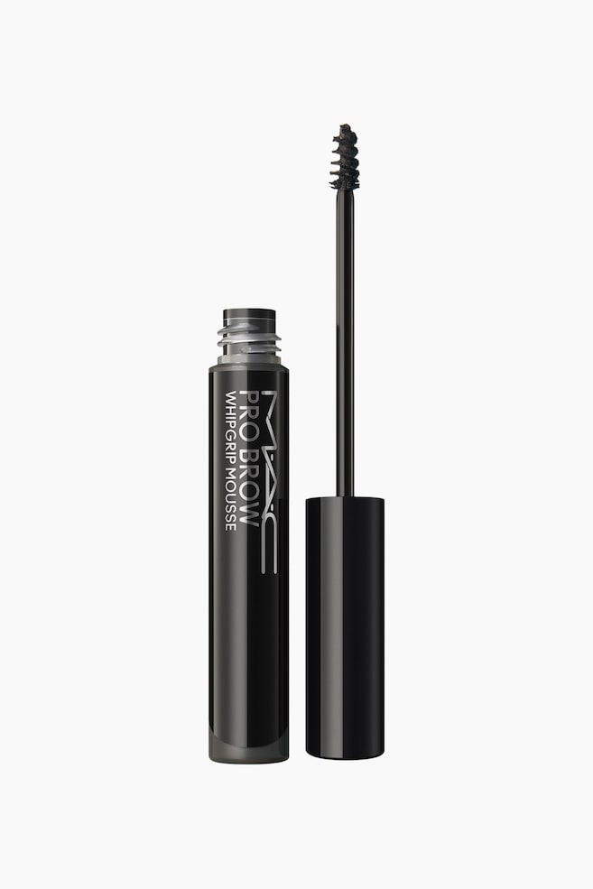 Pro Brow Whipgrip Mousse stÃ¥r oprejst og viser en Ã¥ben, cylindrisk sort tube med sÃ¸lvfarvet lodret branding sammen med den separate applikatorstav. Applikatorstaven stÃ¥r lodret og afslÃ¸rer en glat sort cylindrisk hÃ¦tte samt en tynd skaft toppet med en lille, tilspidset spoolie-bÃ¸rste dÃ¦kket af mÃ¸rkebrun produkt. - 1